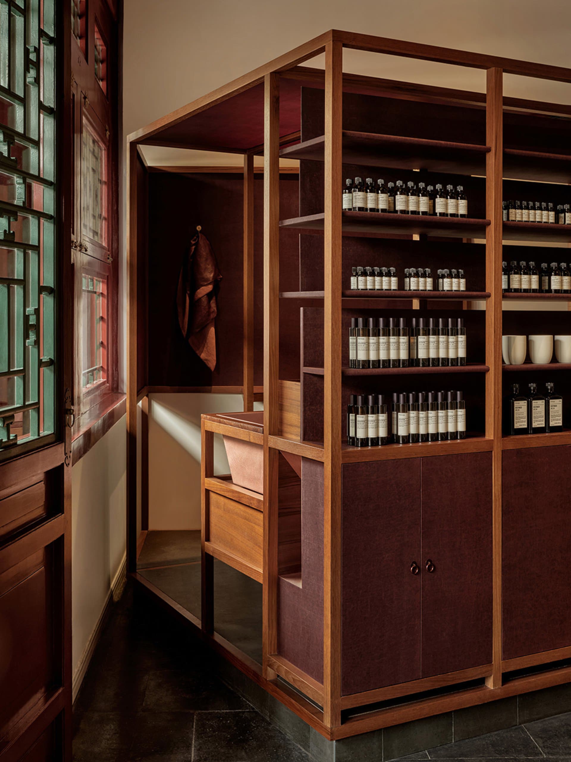 Modern retail storefront with wooden shelving and leather-covered cabinets displaying a variety of products.