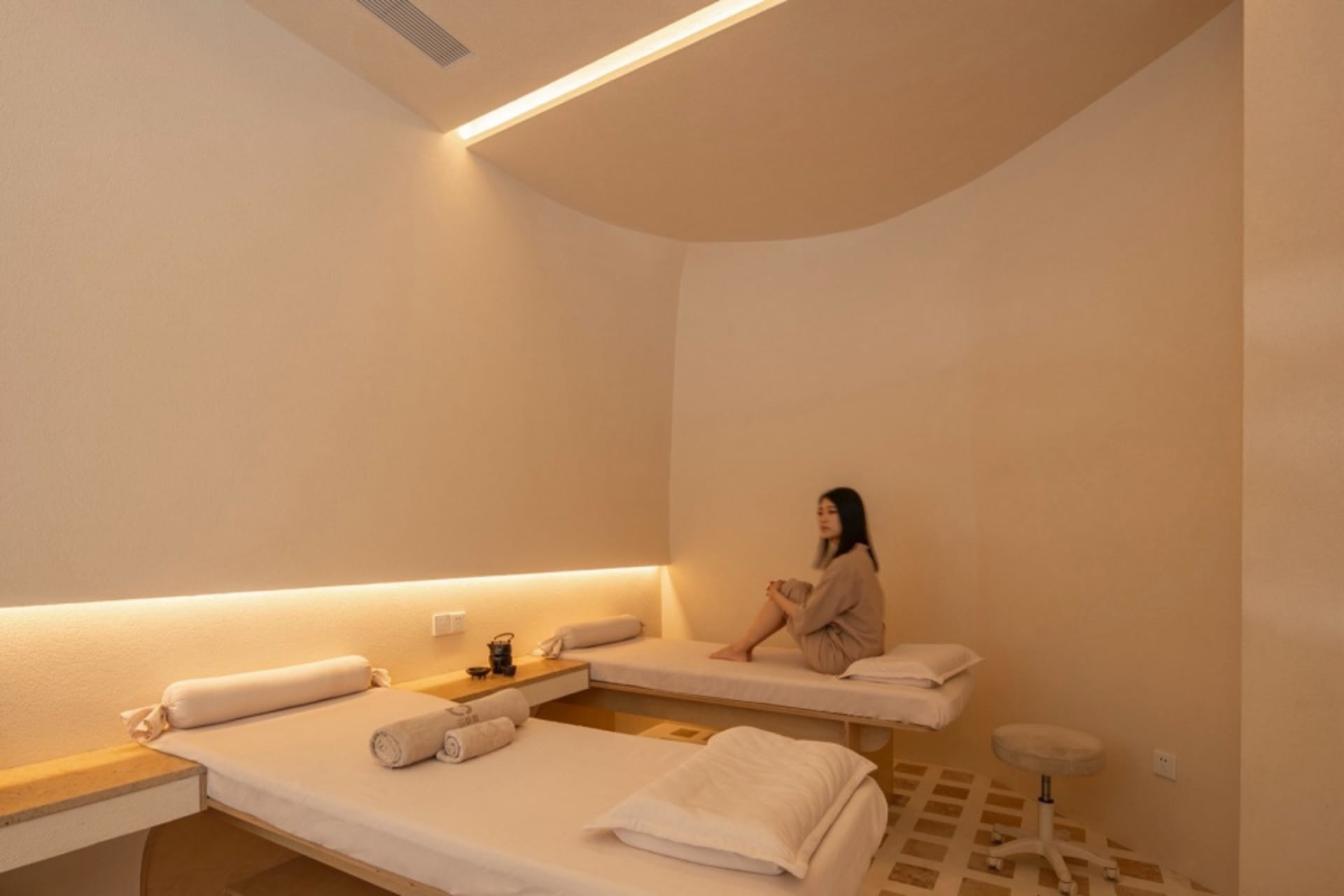 A modern spa relaxation room with neutral-toned materials and calming ambiance.