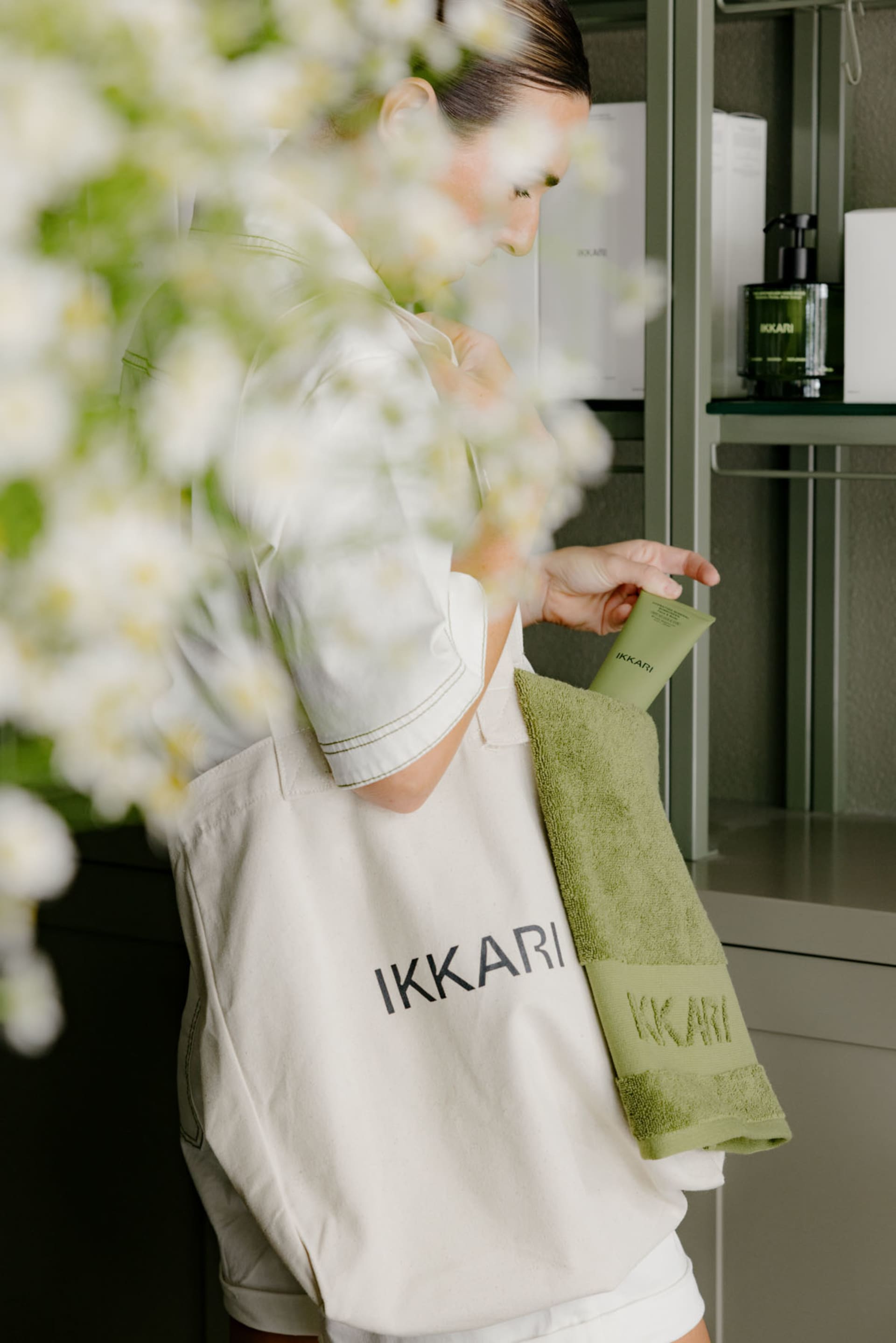 一位人士手持綠色 Ikkari 袋,內裝浴巾與盥洗用品。