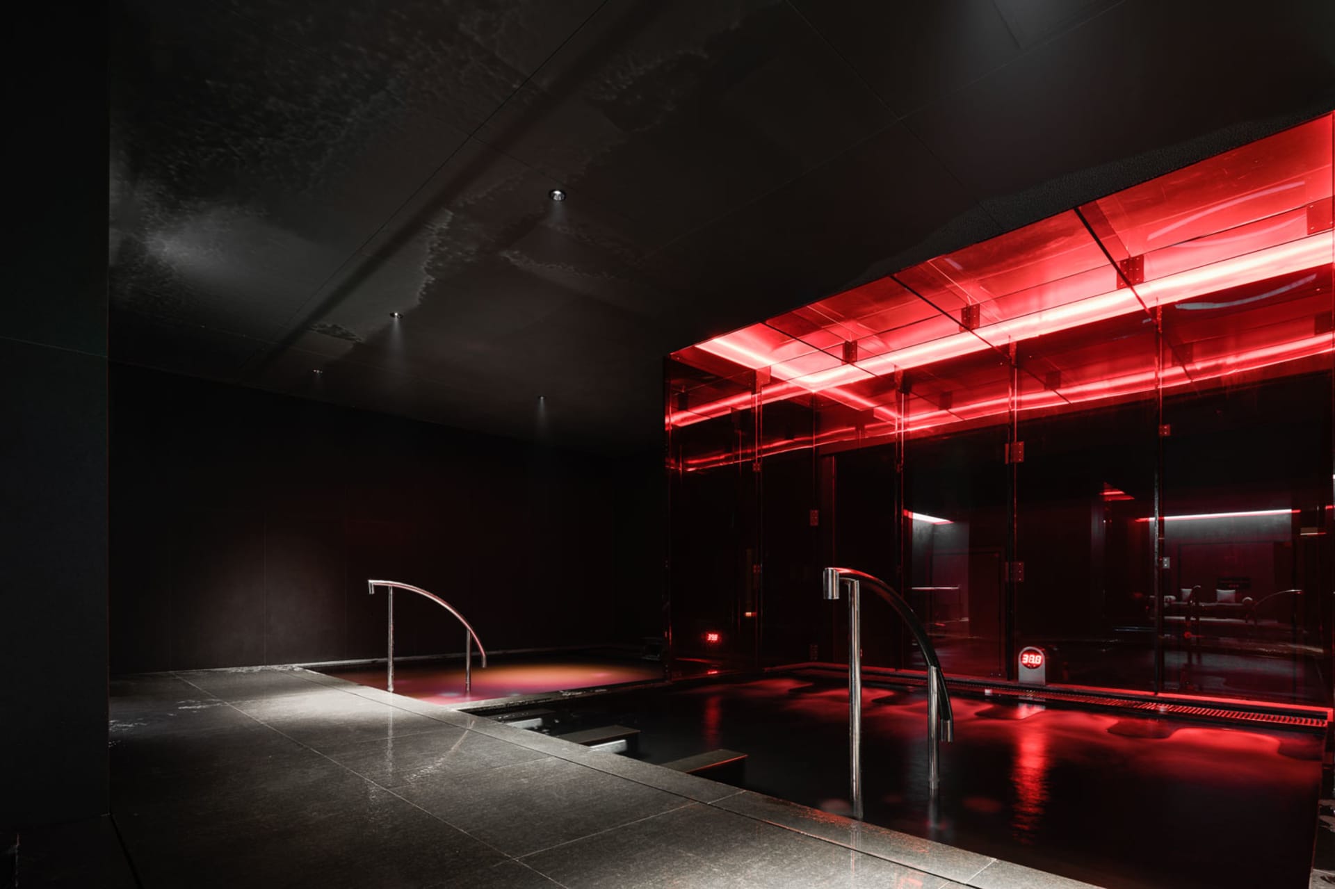 Modern minimalist design with glass walls and metal accents, featuring a hot tub.