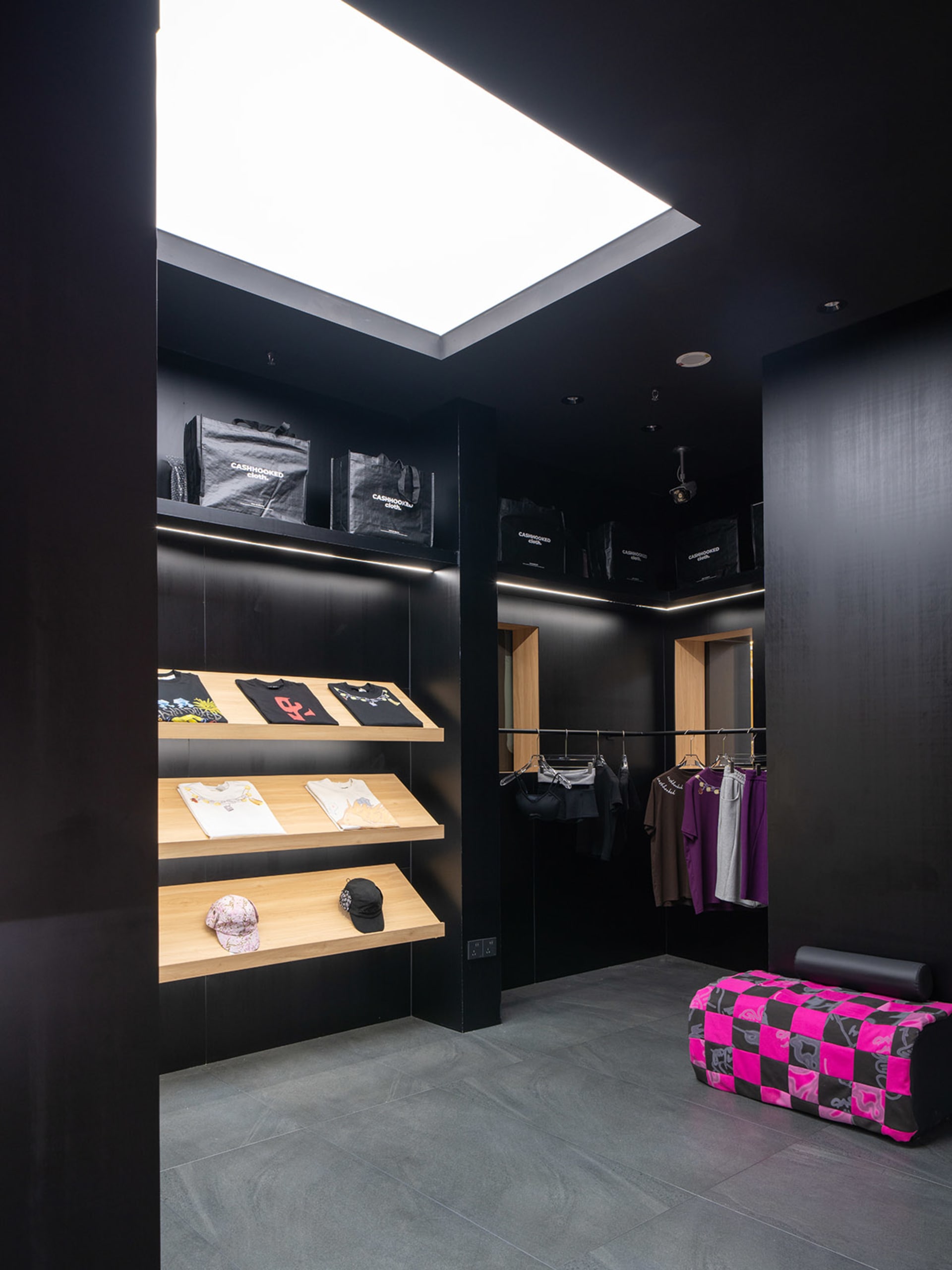 現代零售店深色室內,展示架上陳列服裝與配件。