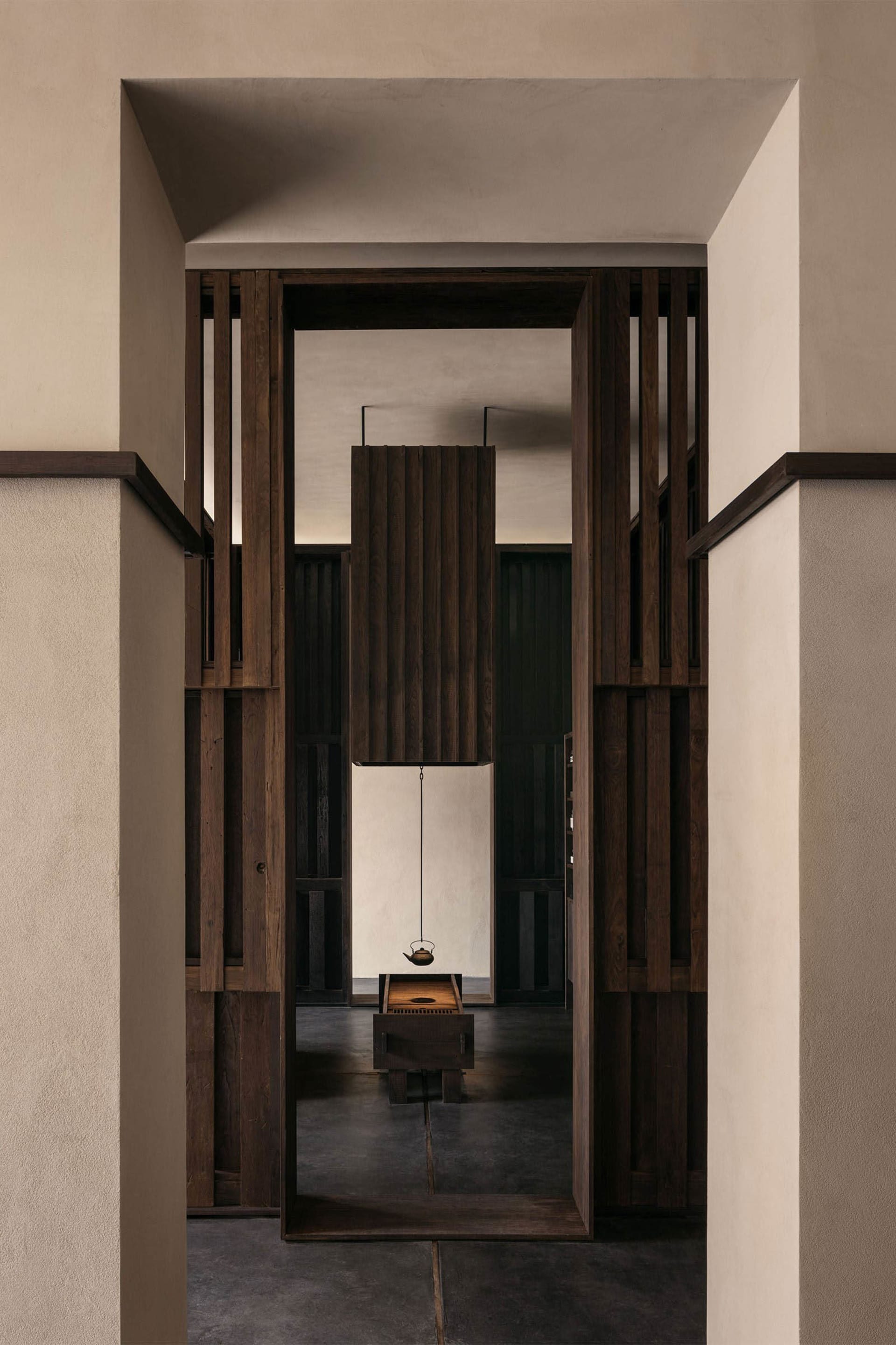 A modern tea room with wooden walls and a hanging kettle over a wooden table.