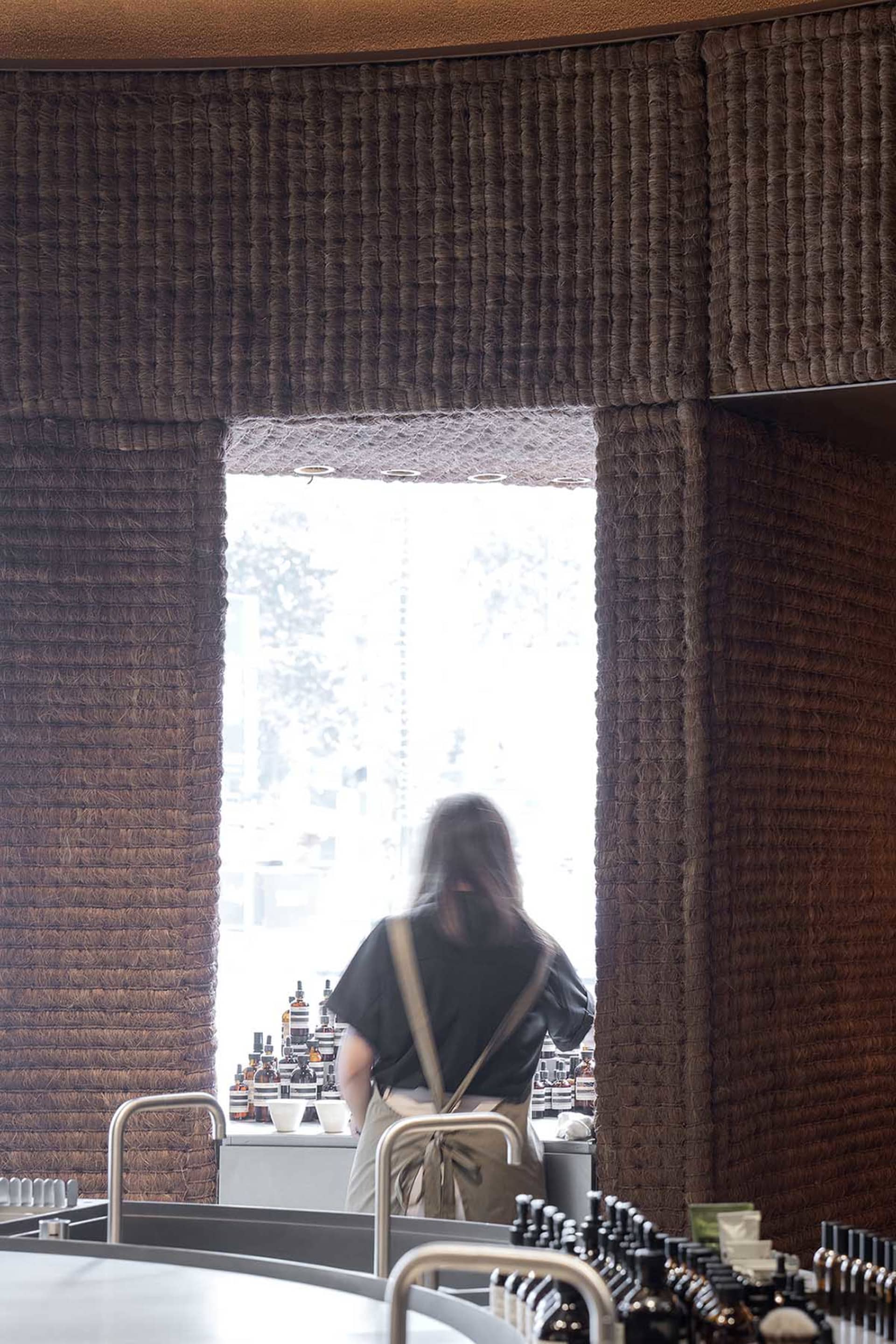 A textured wall paneling restaurant counter with a person standing behind it.