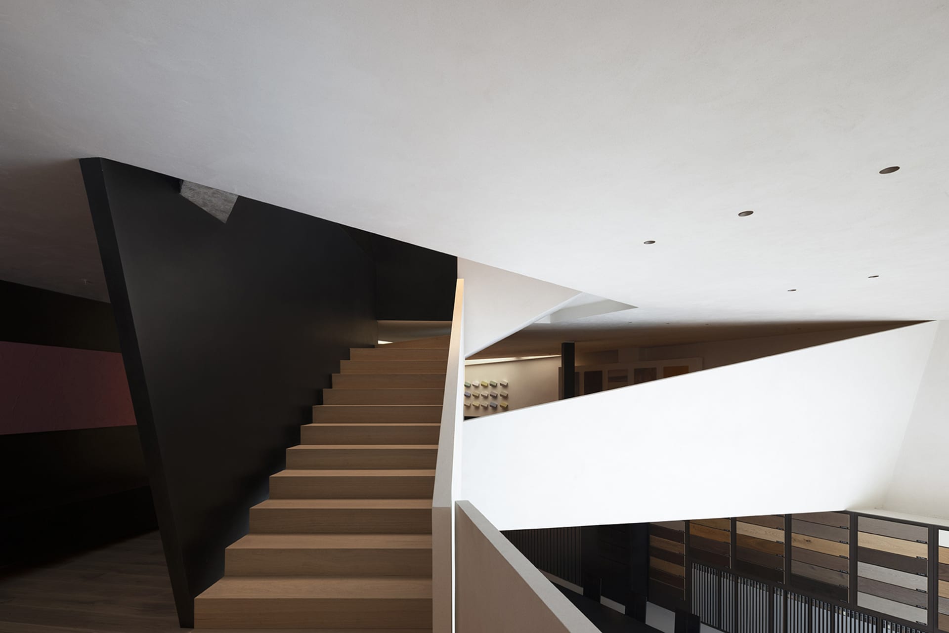 Modern, minimalist interior design featuring a wooden staircase with concrete walls.