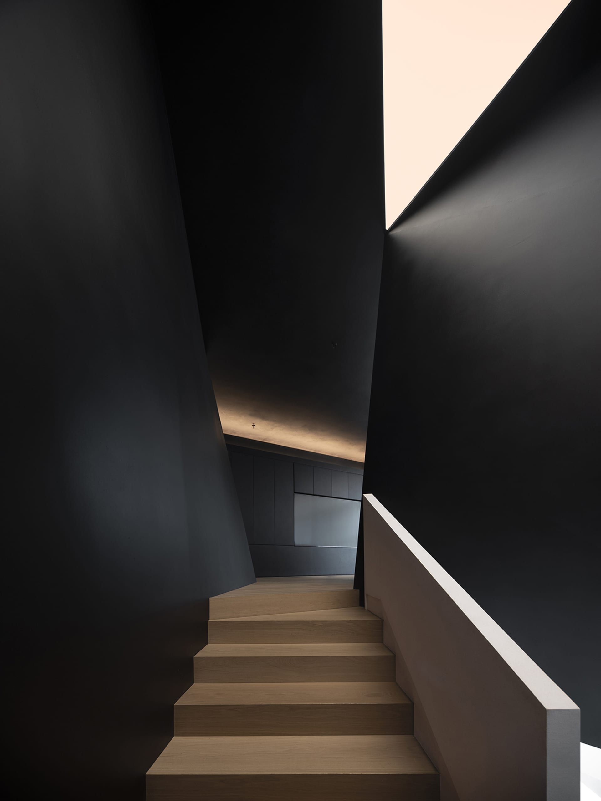 Modern interior design featuring wooden stairs and dark walls.