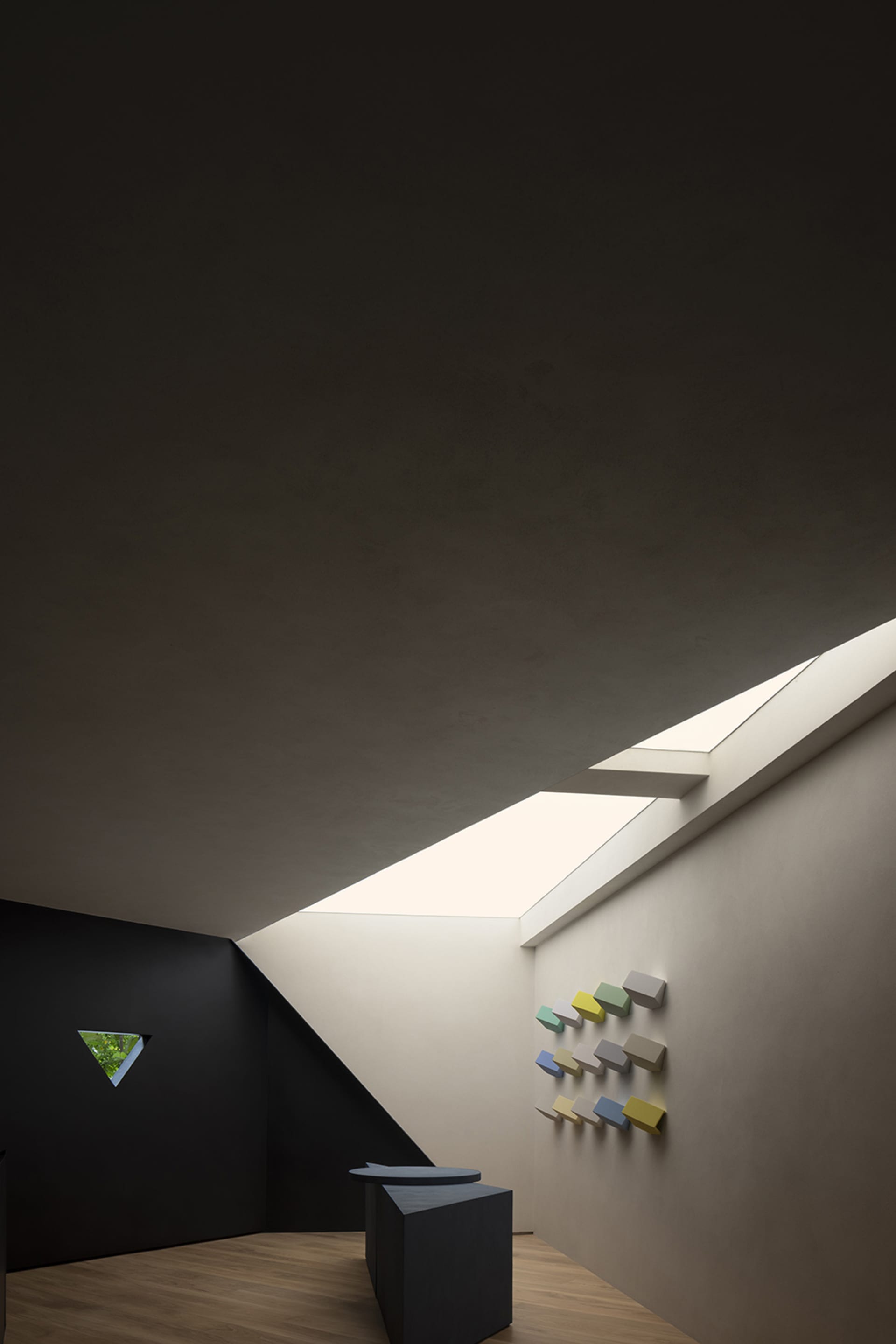 A modern, minimalist architectural space with concrete walls and a skylight.
