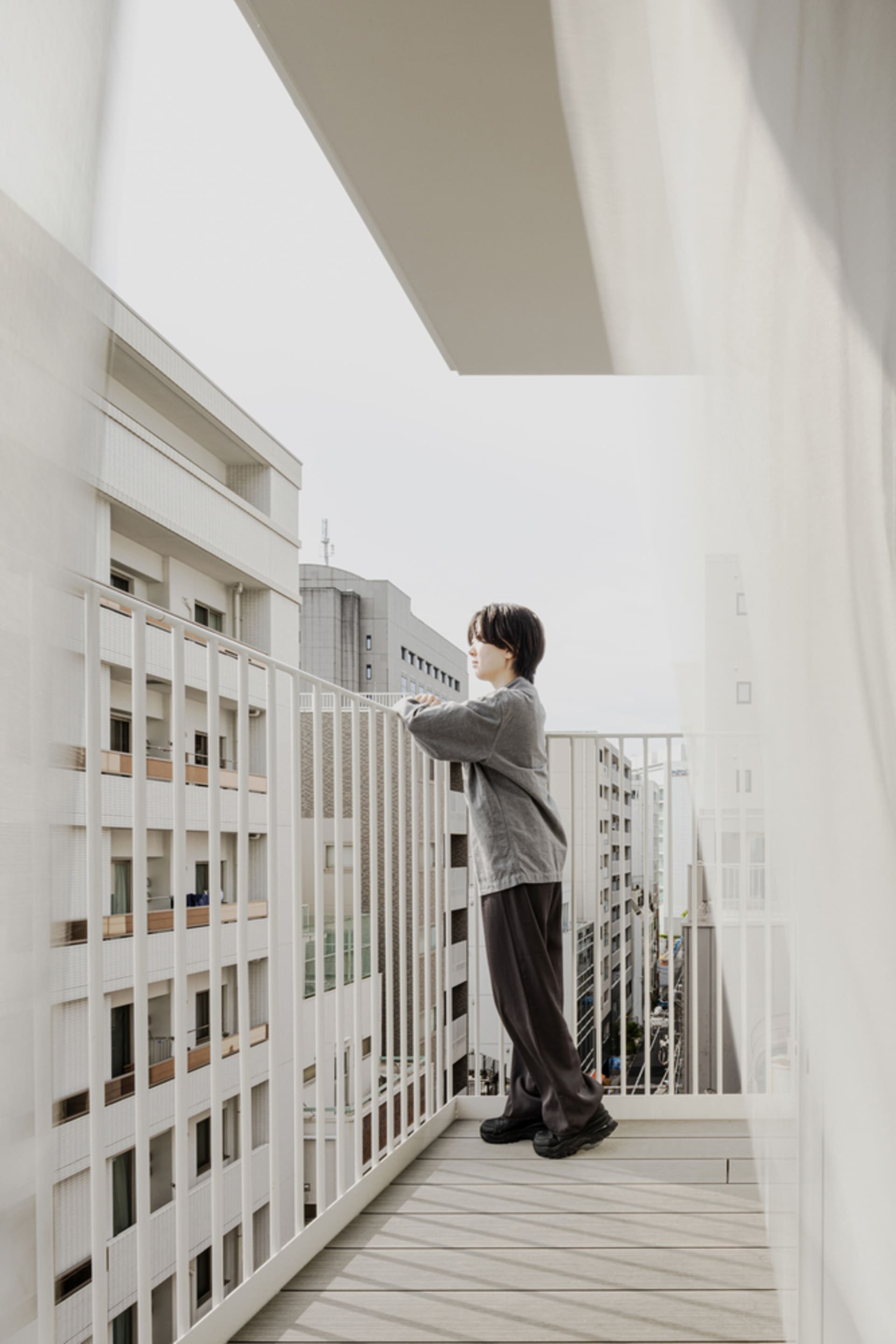 A minimalist balcony with a wooden deck overlooking a cityscape.