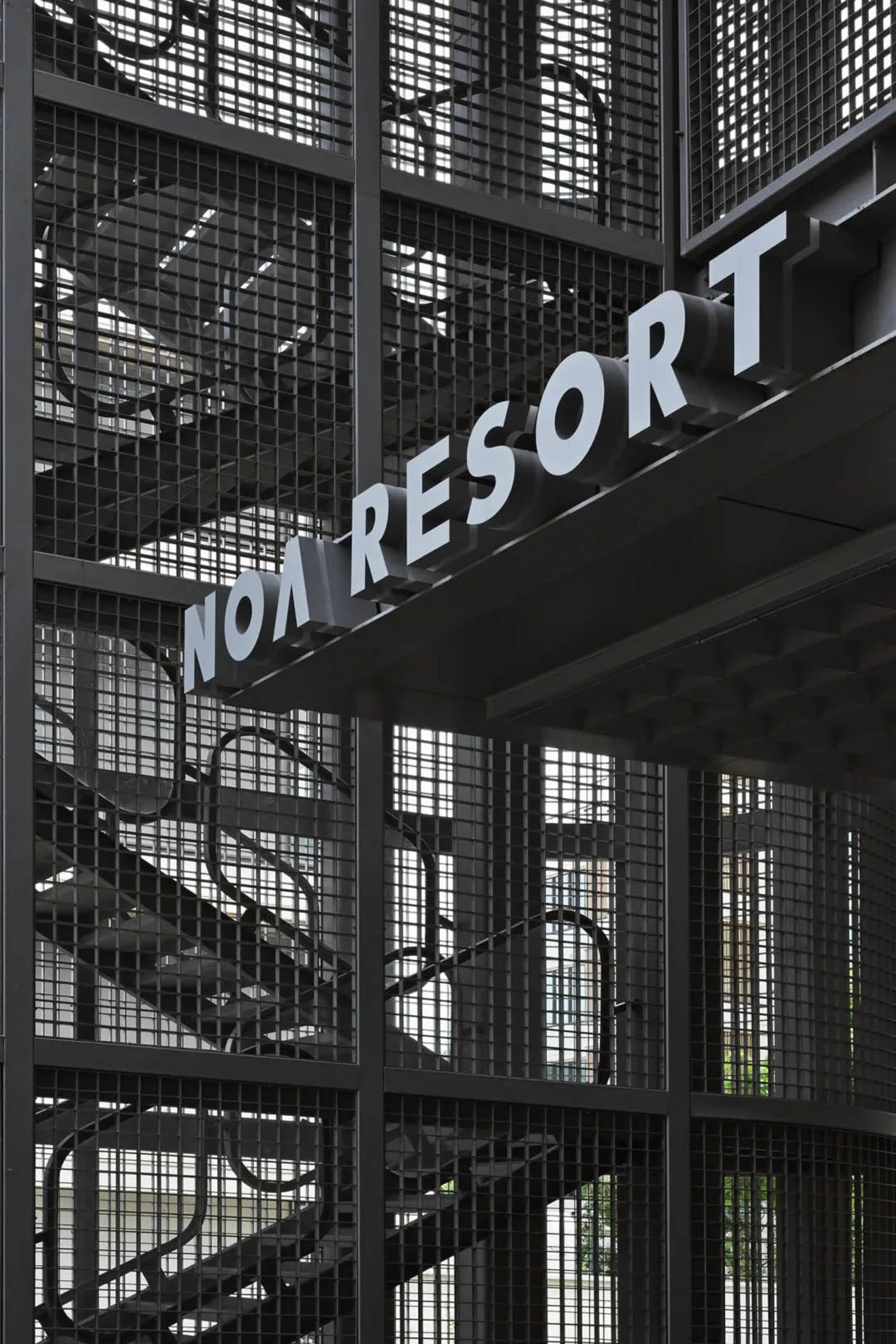 A metal wall sign with the text 'Noa Resort' in an industrial design style.