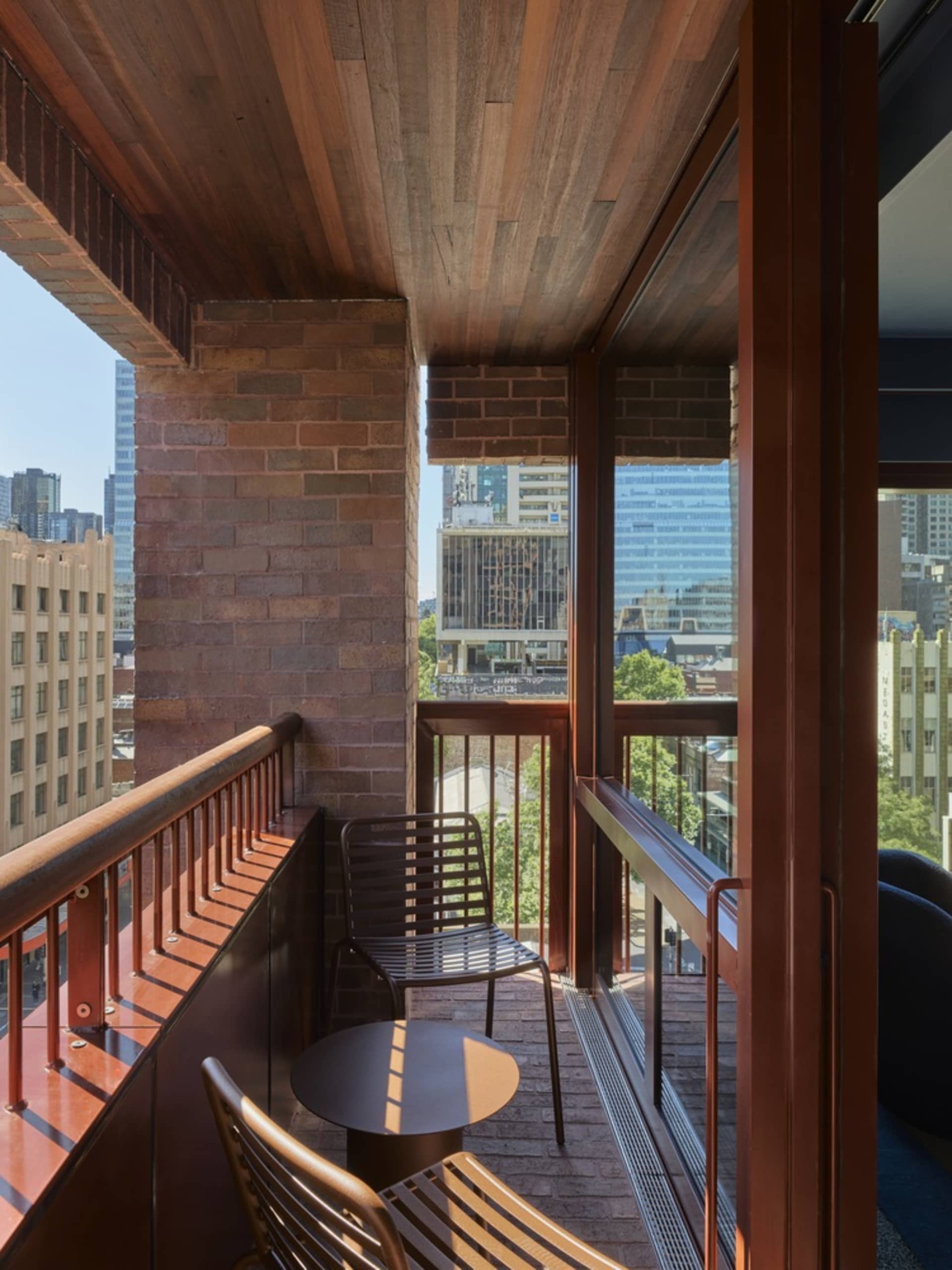 A modern balcony featuring brick walls and metal railings.