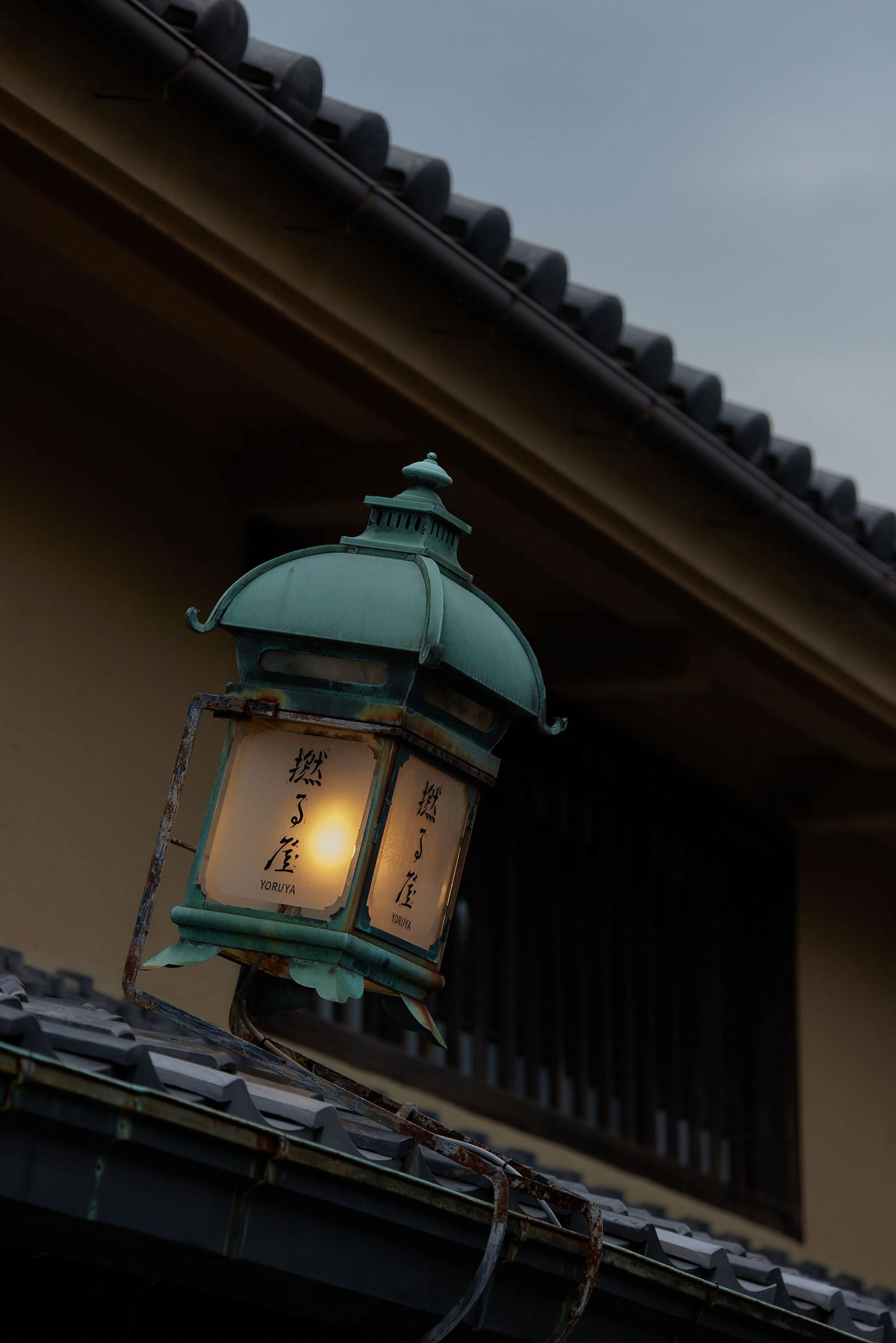 A traditional streetlight made of metal hanging on a roof.