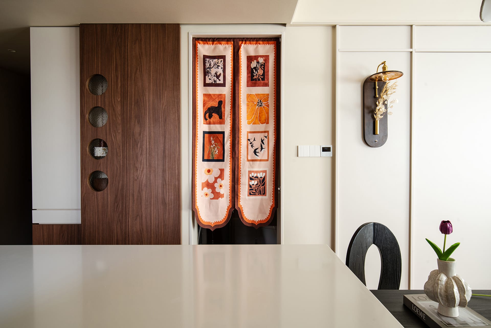 View of a minimalist kitchen featuring an orange printed door with various decorative patches.