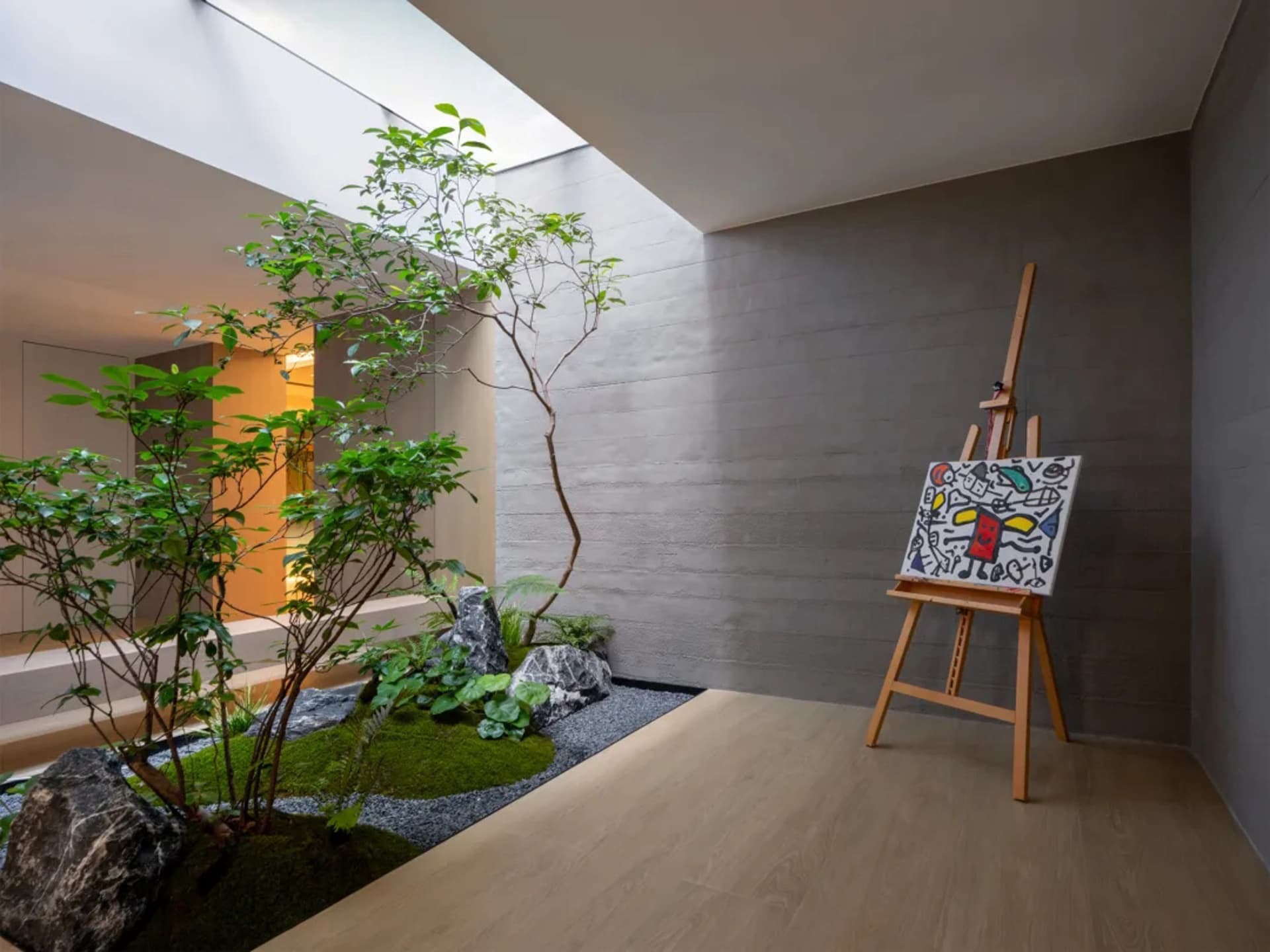 現代室內花園空間,搭配混凝土牆面、木質地板與裝飾岩石。