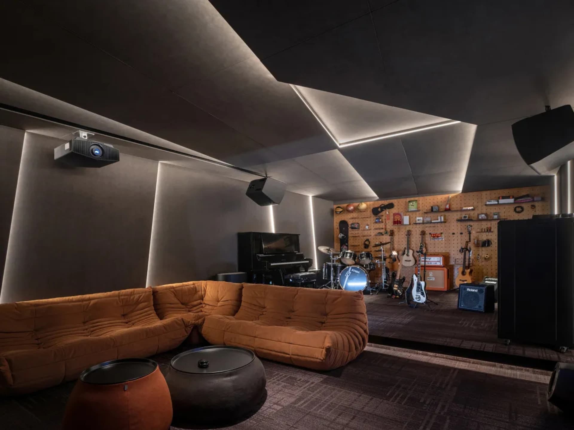 A spacious industrial music studio featuring a plush sofa, a variety of musical instruments, and acoustic foam panels on the 