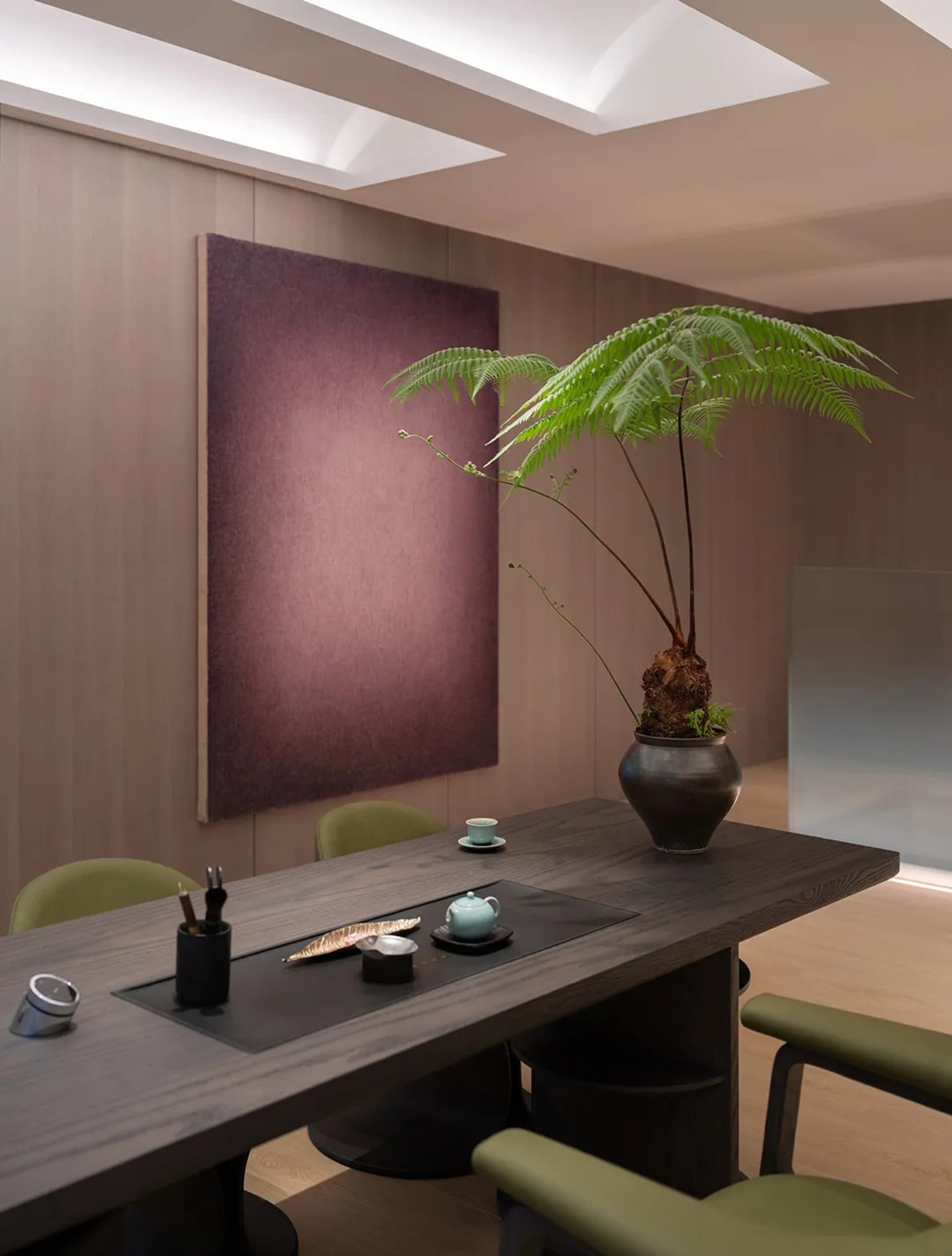 Modern office space featuring a wooden table with green plants and minimalist interior design.