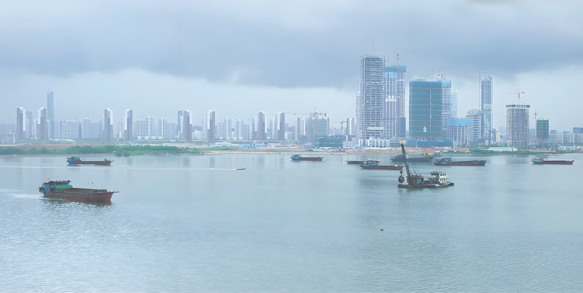 A cityscape featuring modern buildings and a marina with boats.