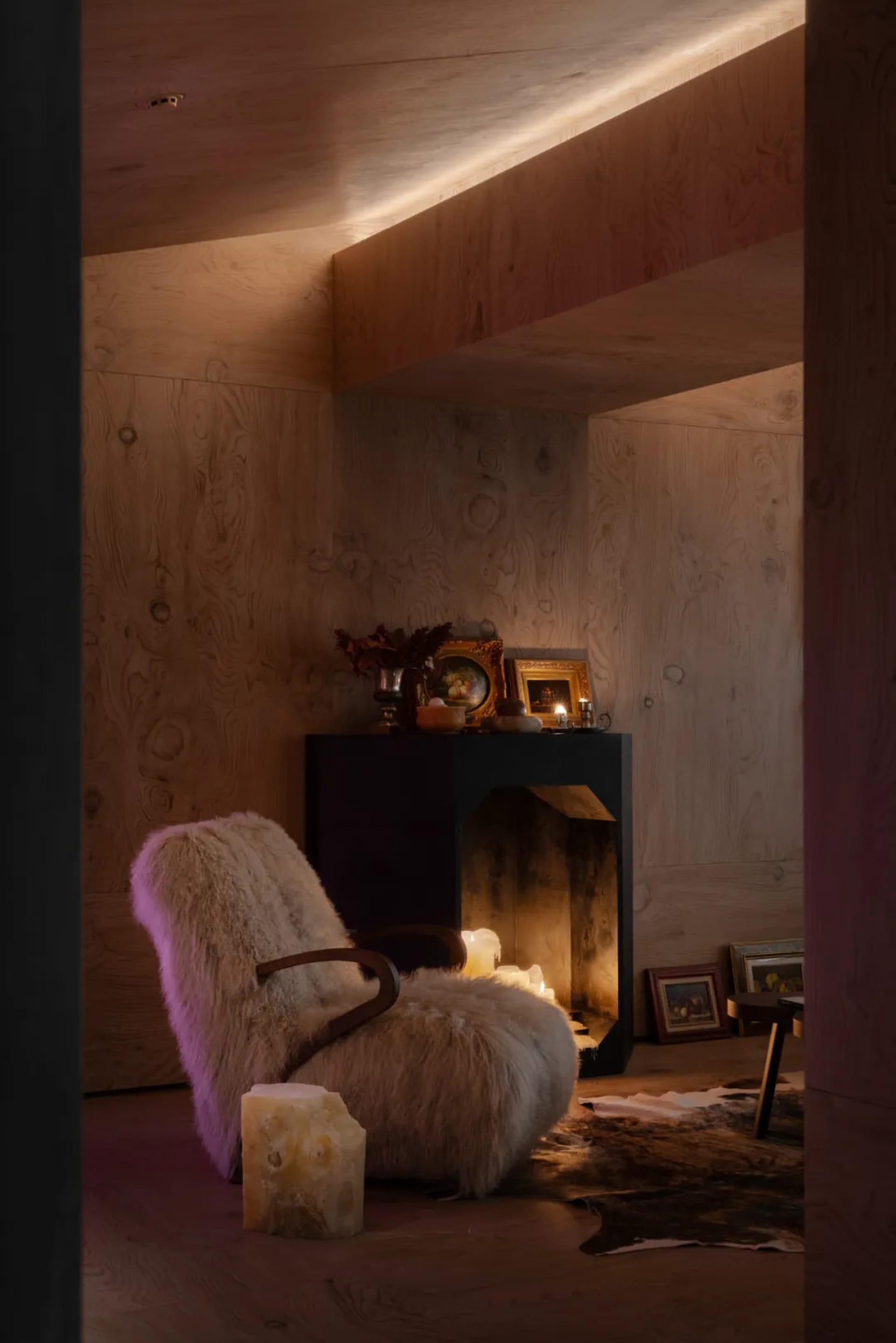 Industrial-style lounge area featuring a wooden armchair, candles, and framed artwork.
