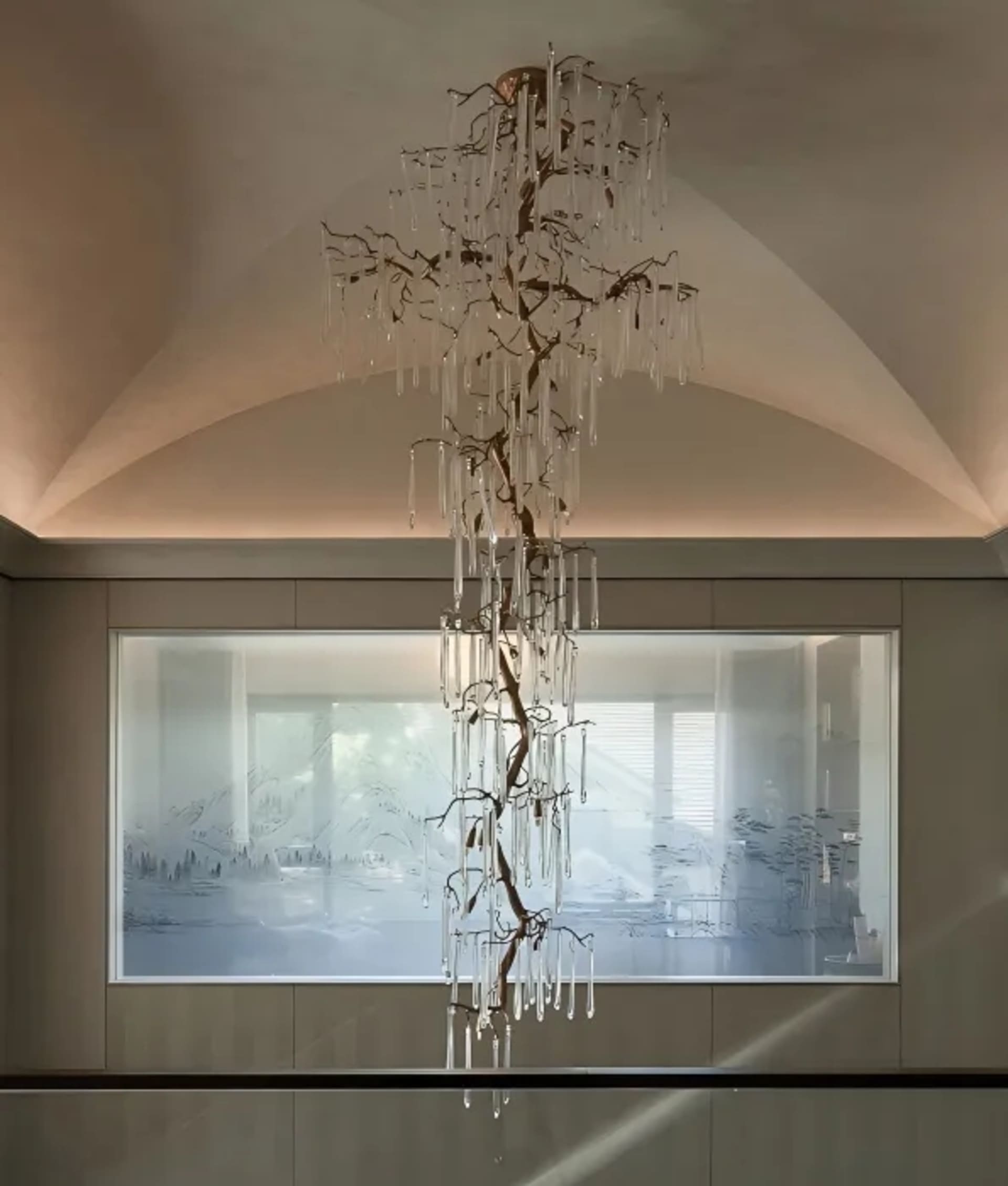 Modern interior design featuring a glass and copper chandelier with pendant lights hanging from it.