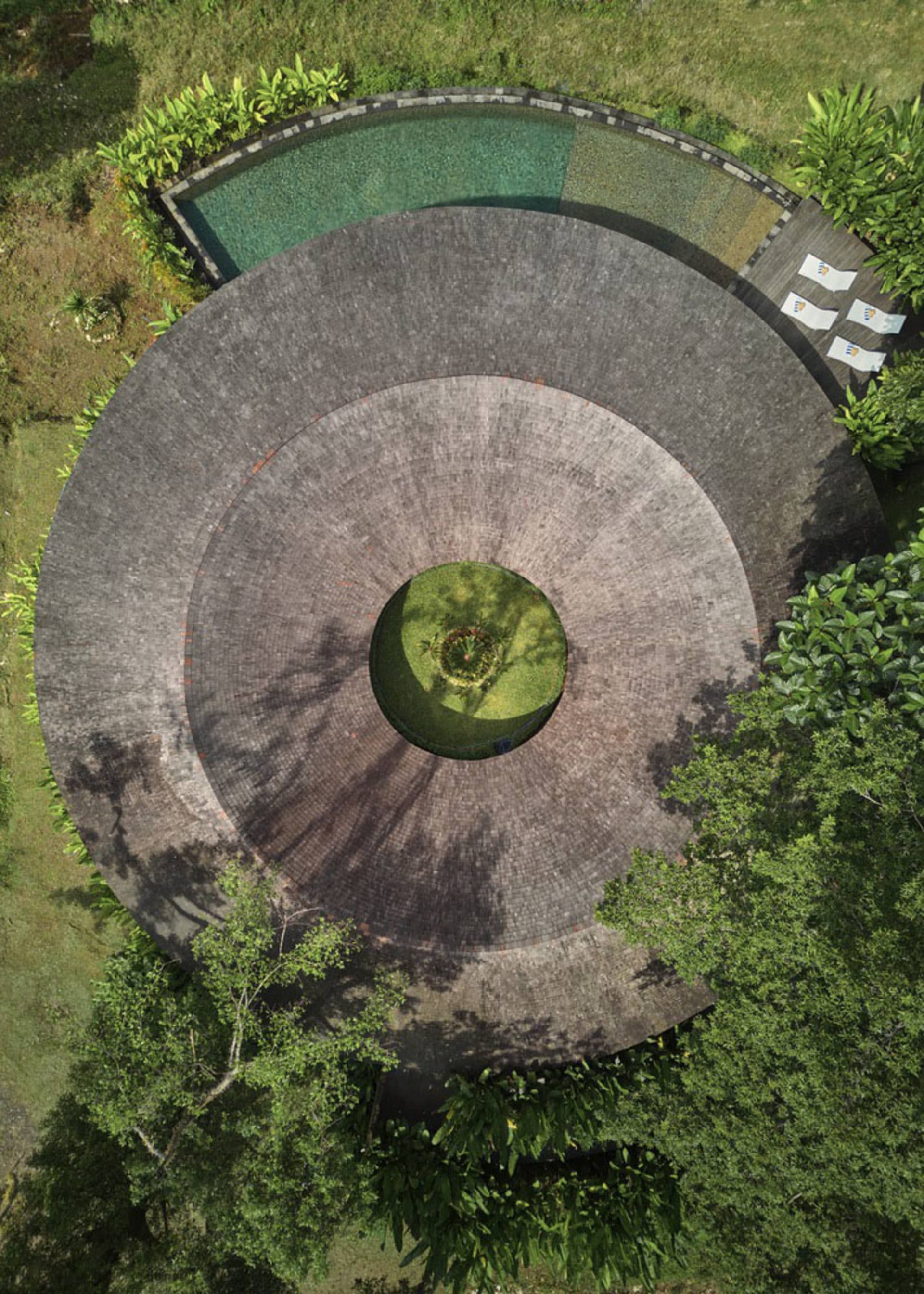 Circular brick pathway with greenery and water feature in a landscaped environment