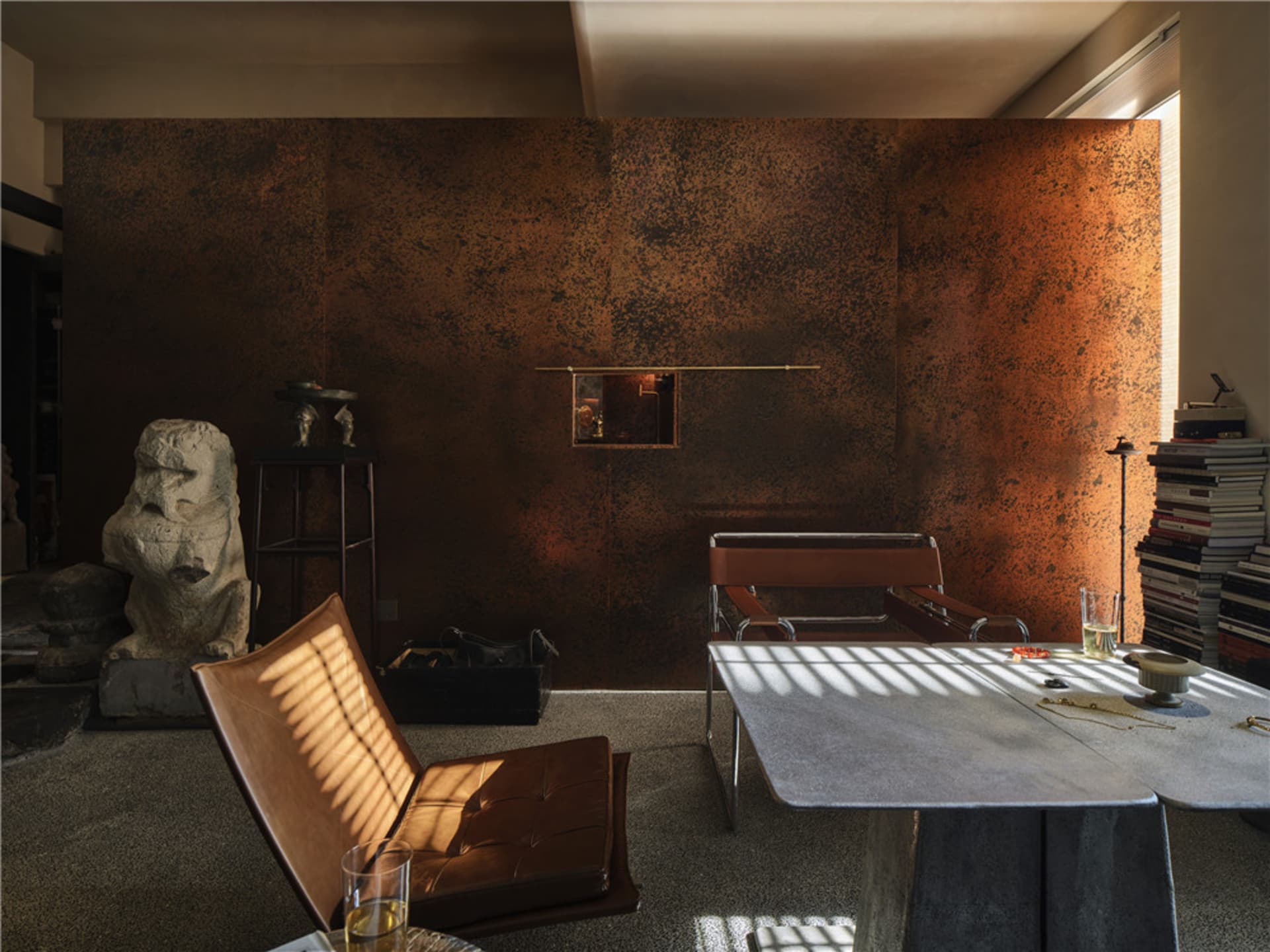 A living room featuring a metallic textured wall, a brown leather chair, and a table.