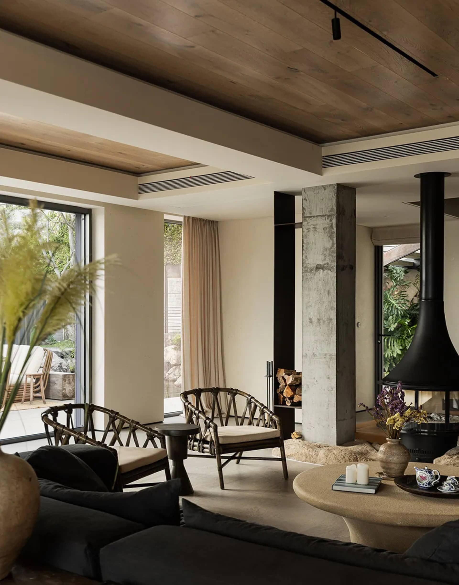 Modern living room with concrete walls and floor, featuring a circular table and black furniture, providing a warm and cozy a