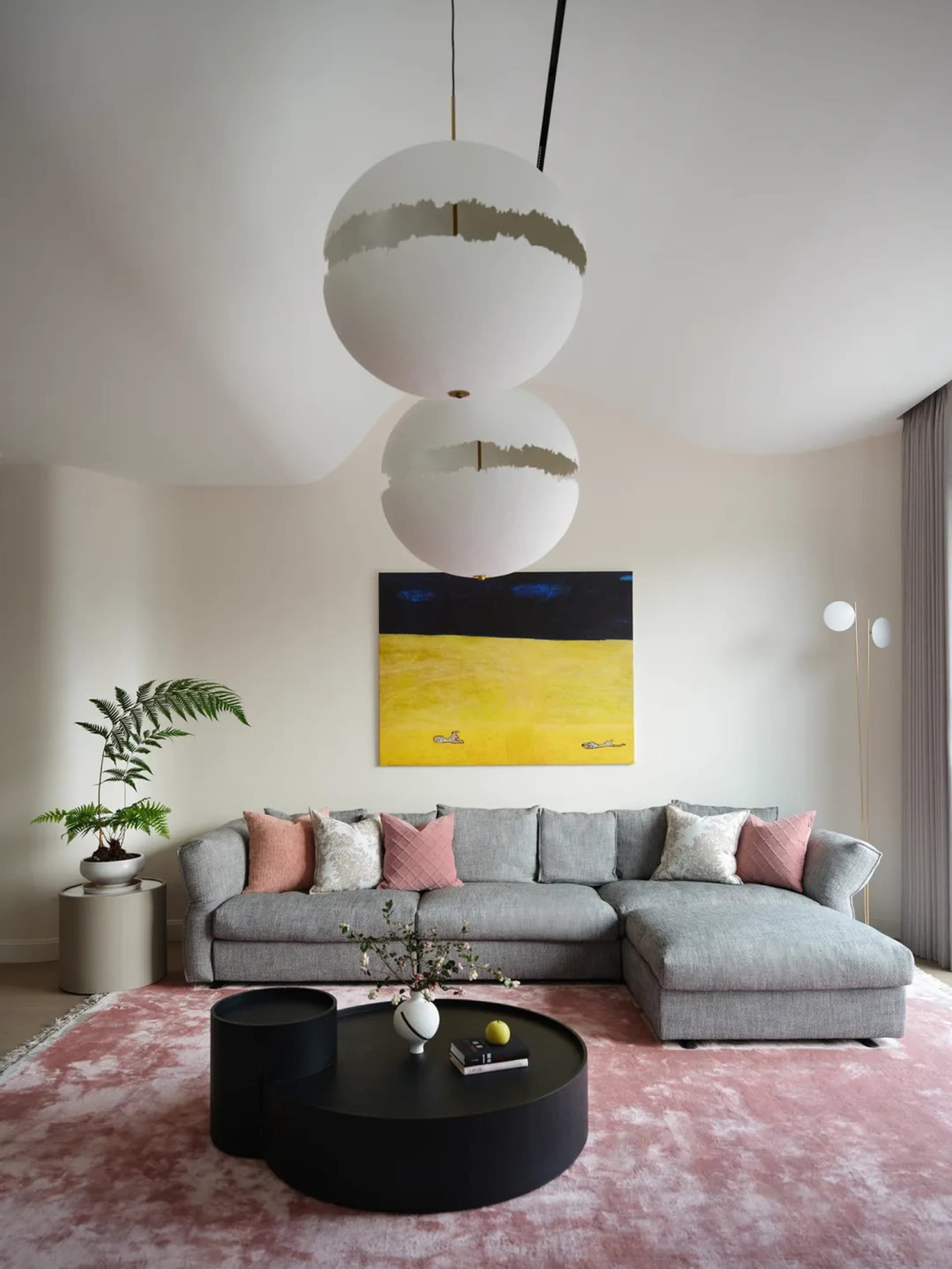 A modern living room with a circular lamp, contemporary couch, and pink rug.