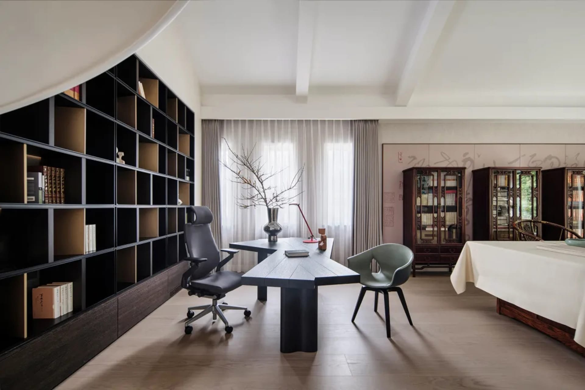 A modern office space featuring a wooden desk, black office chairs, and a large wooden shelving unit.