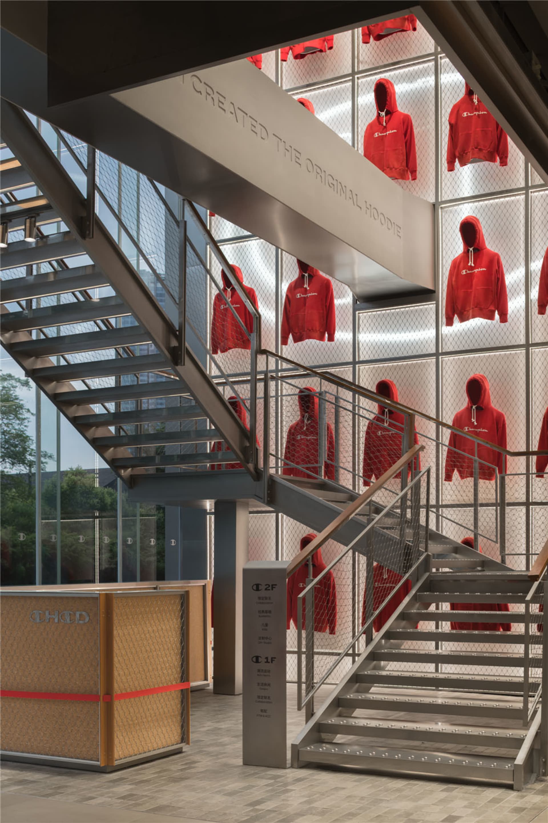 Retail store featuring a metal mesh display wall showcasing red hoodie sweatshirts.