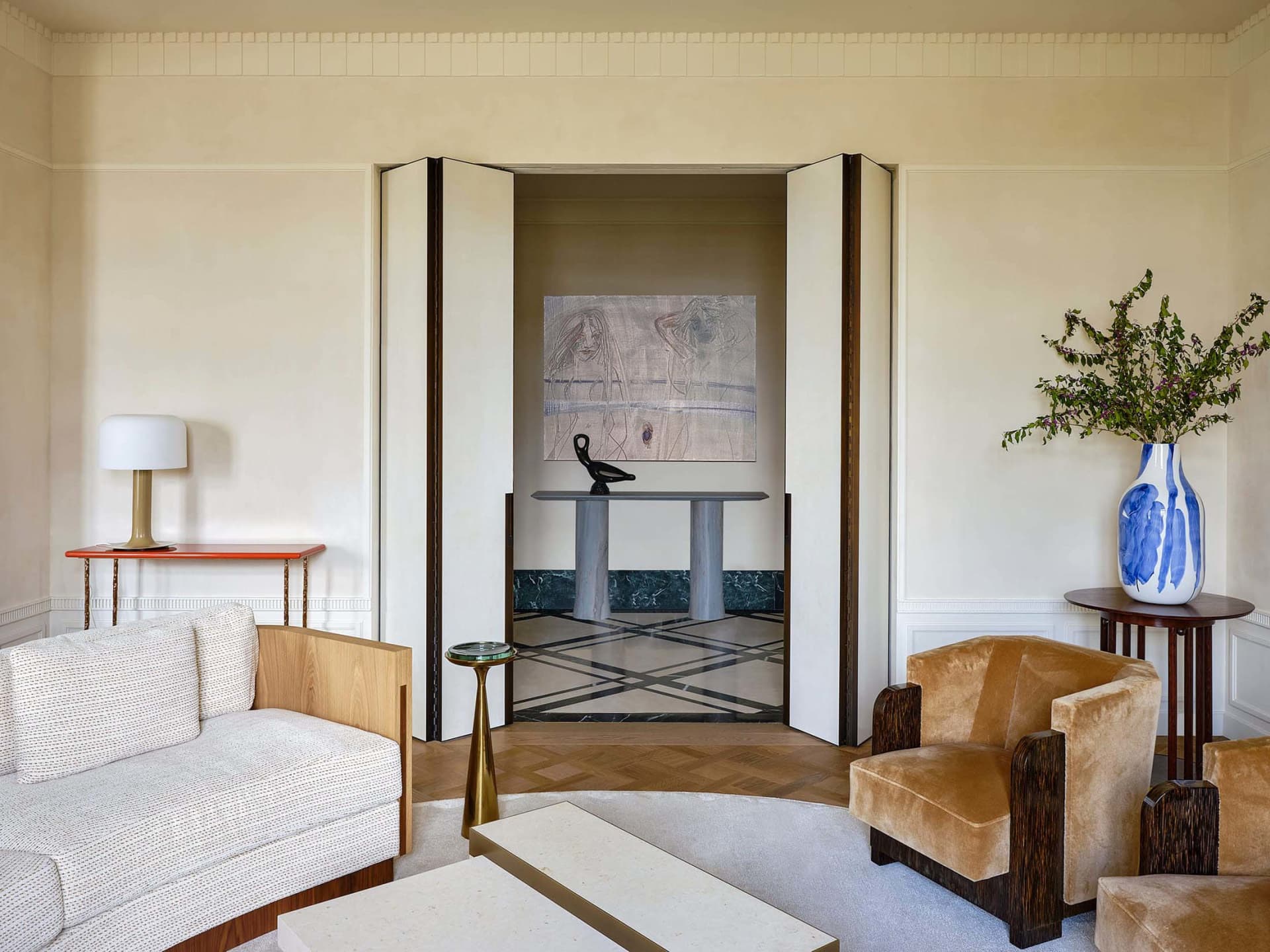 Modern living room featuring white walls, wooden floor, and a white sofa with a side table and lamp, leading to a hallway wit