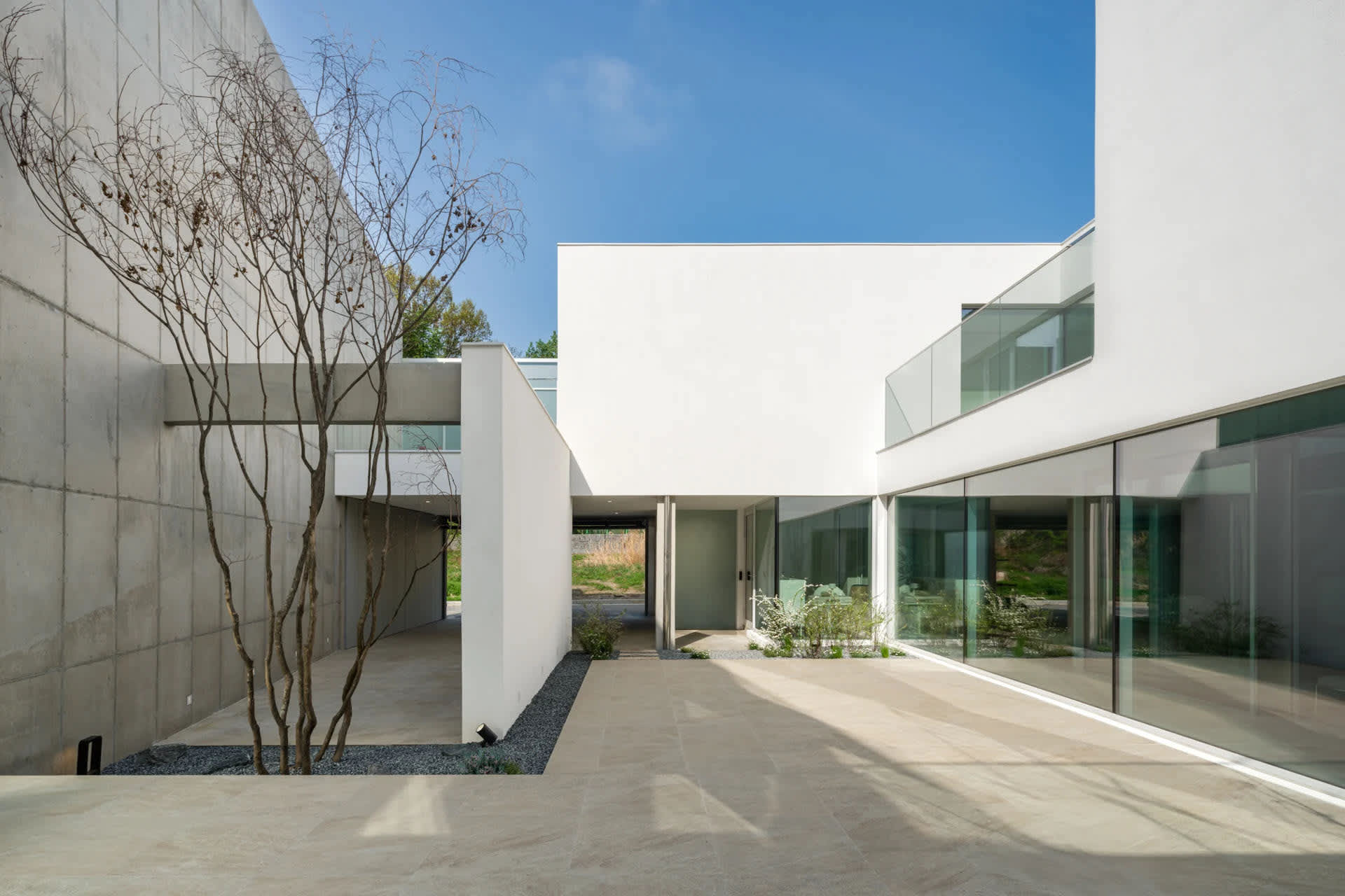 A modern house with white concrete walls and large glass windows.