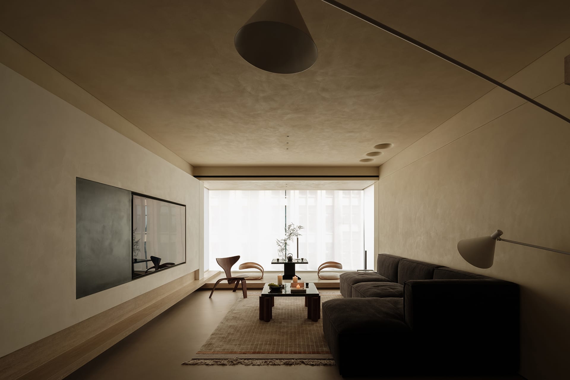 A minimalist living room with neutral-toned walls, a dark sofa, and a low coffee table.