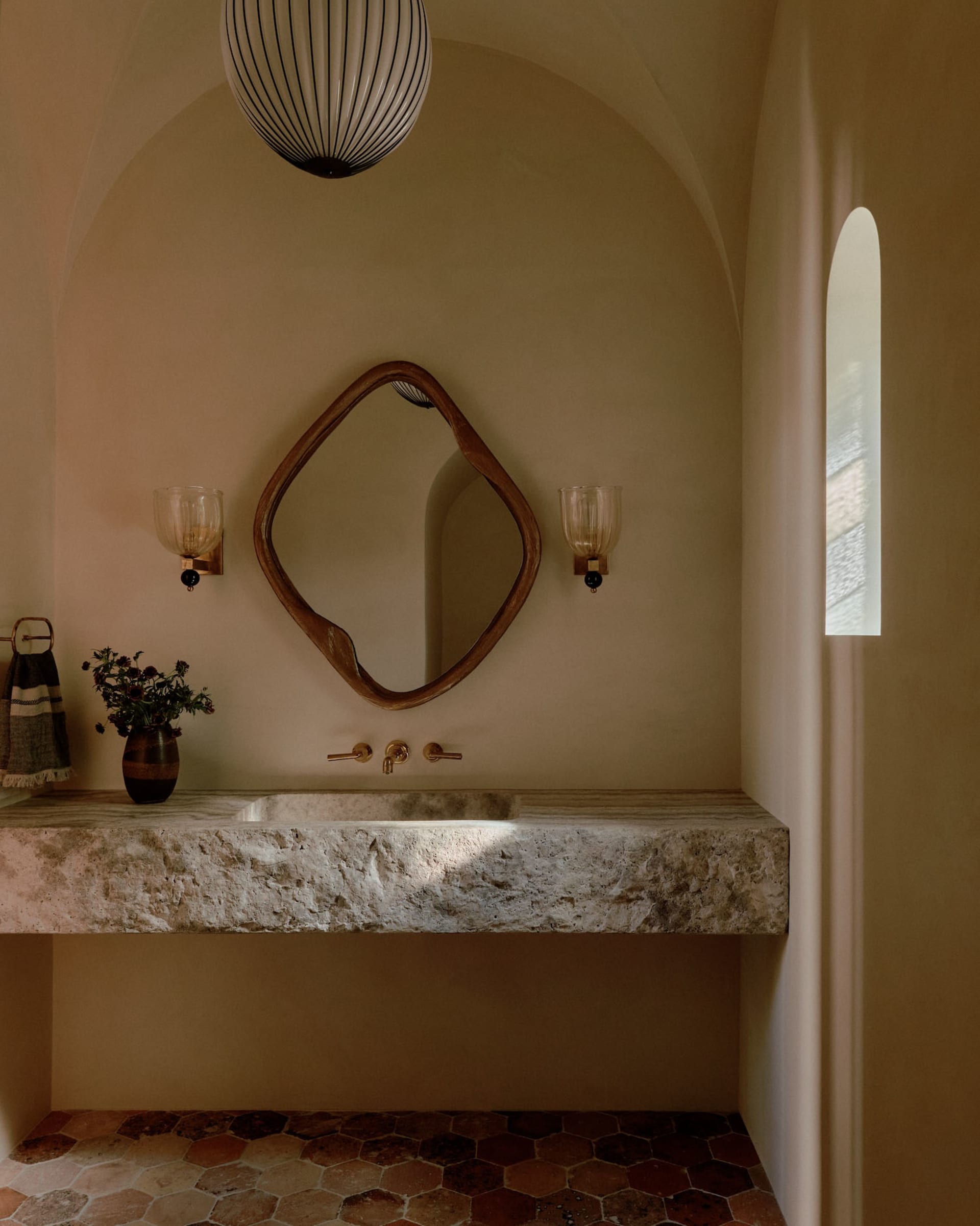 Modern bathroom with a floating concrete sink, a wooden mirror, and a geometric pendant light.