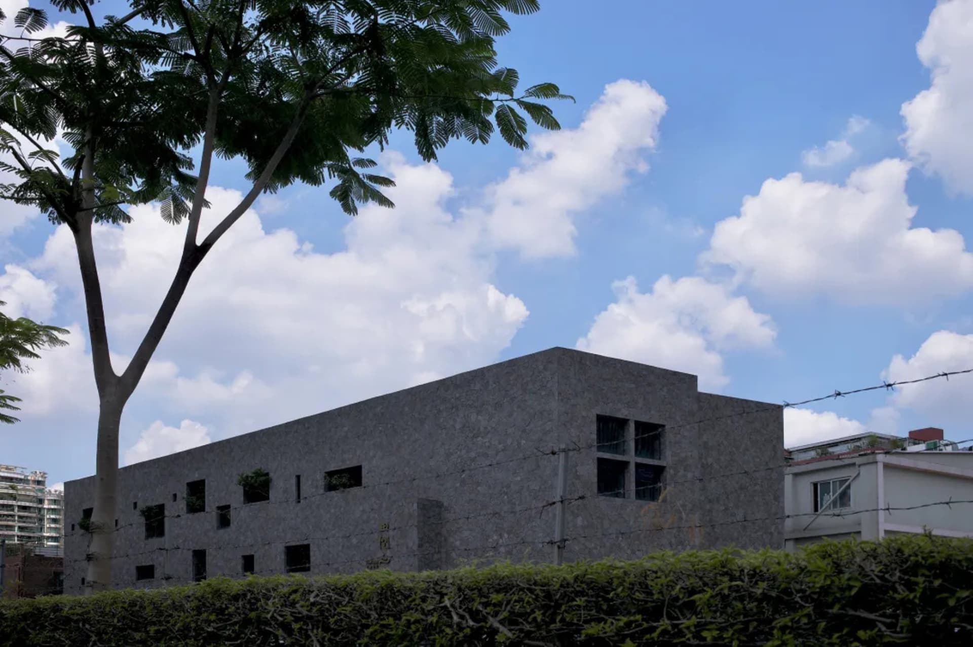 一座擁有混凝土外牆與大型窗戶的現代建築,映襯在藍天白雲之下。