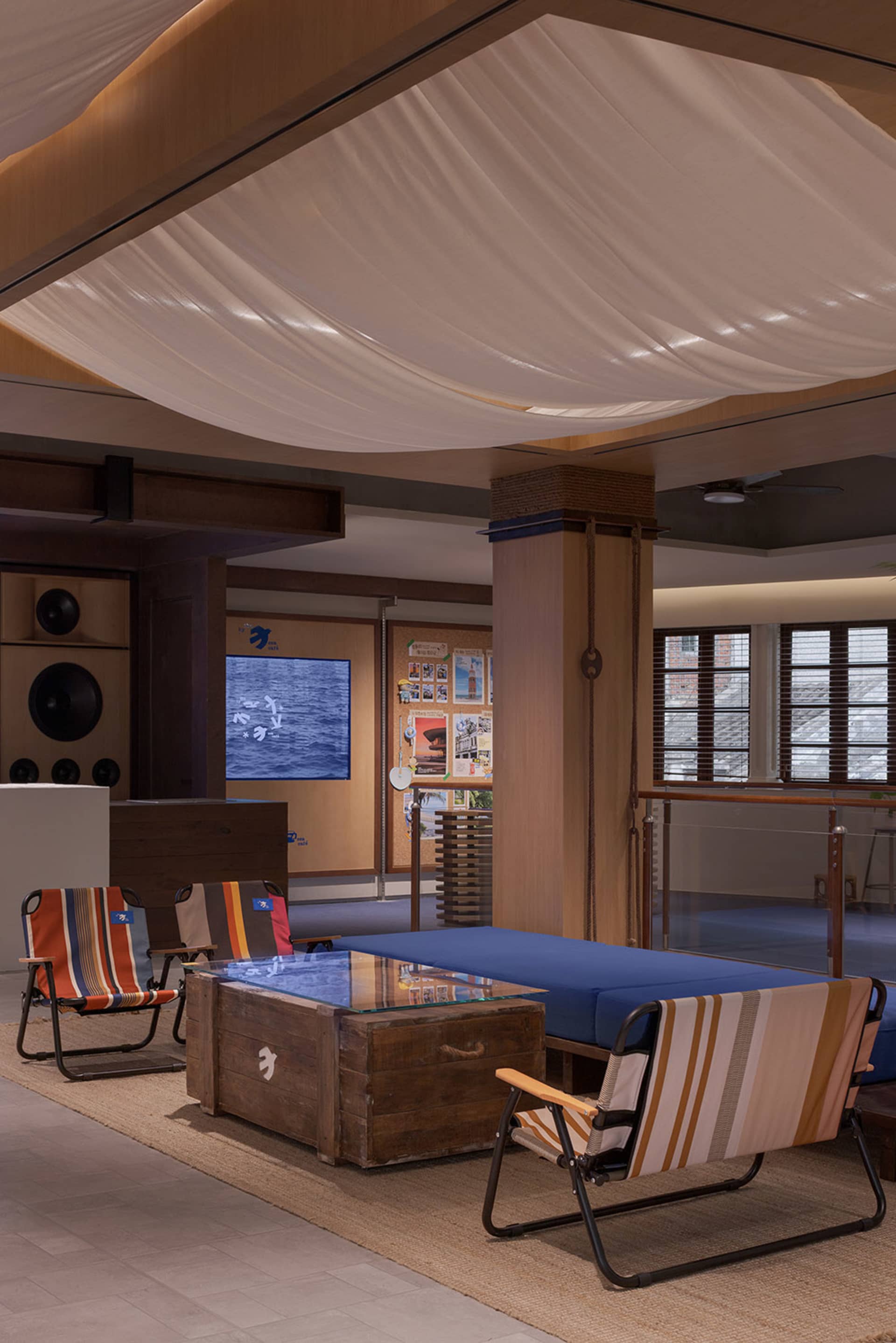 An industrial-style reception lounge with a textured canvas ceiling, wooden floor, and glass coffee table.