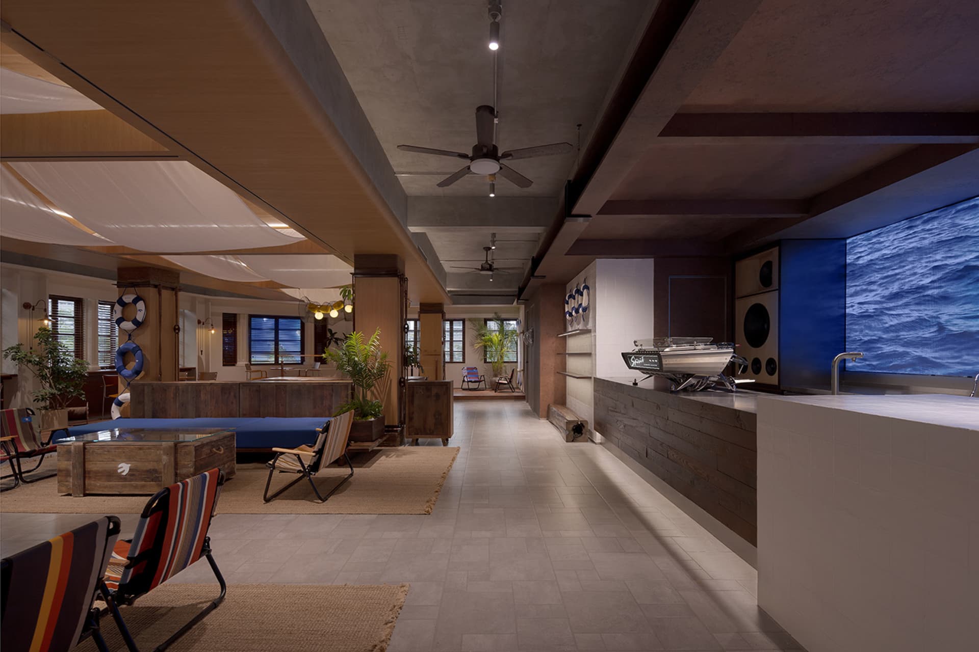 Modern lobby interior with concrete finishes and industrial design elements, featuring a central desk area, seating, and a mo