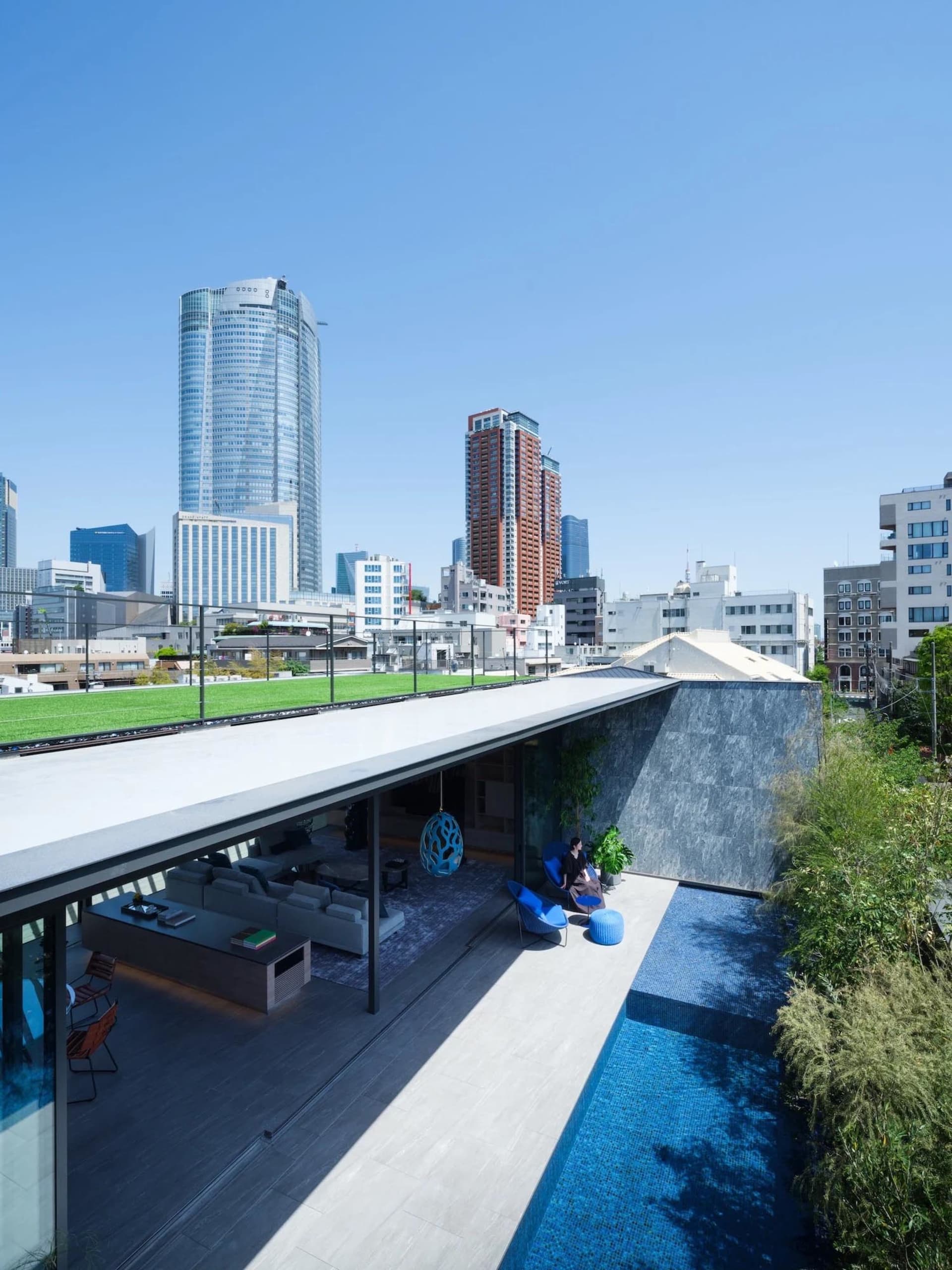 Modern residential rooftop featuring a pool and views of a city skyline.