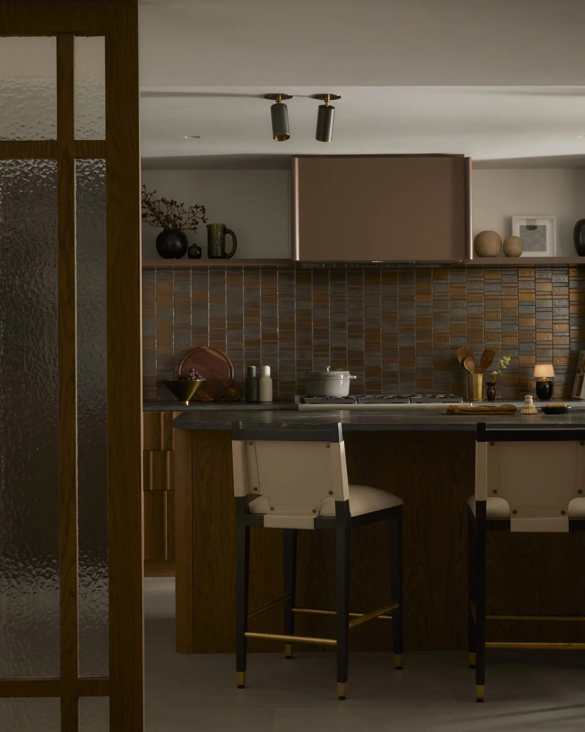 Modern residential kitchen with wood cabinets, metal accents, and stone countertops.