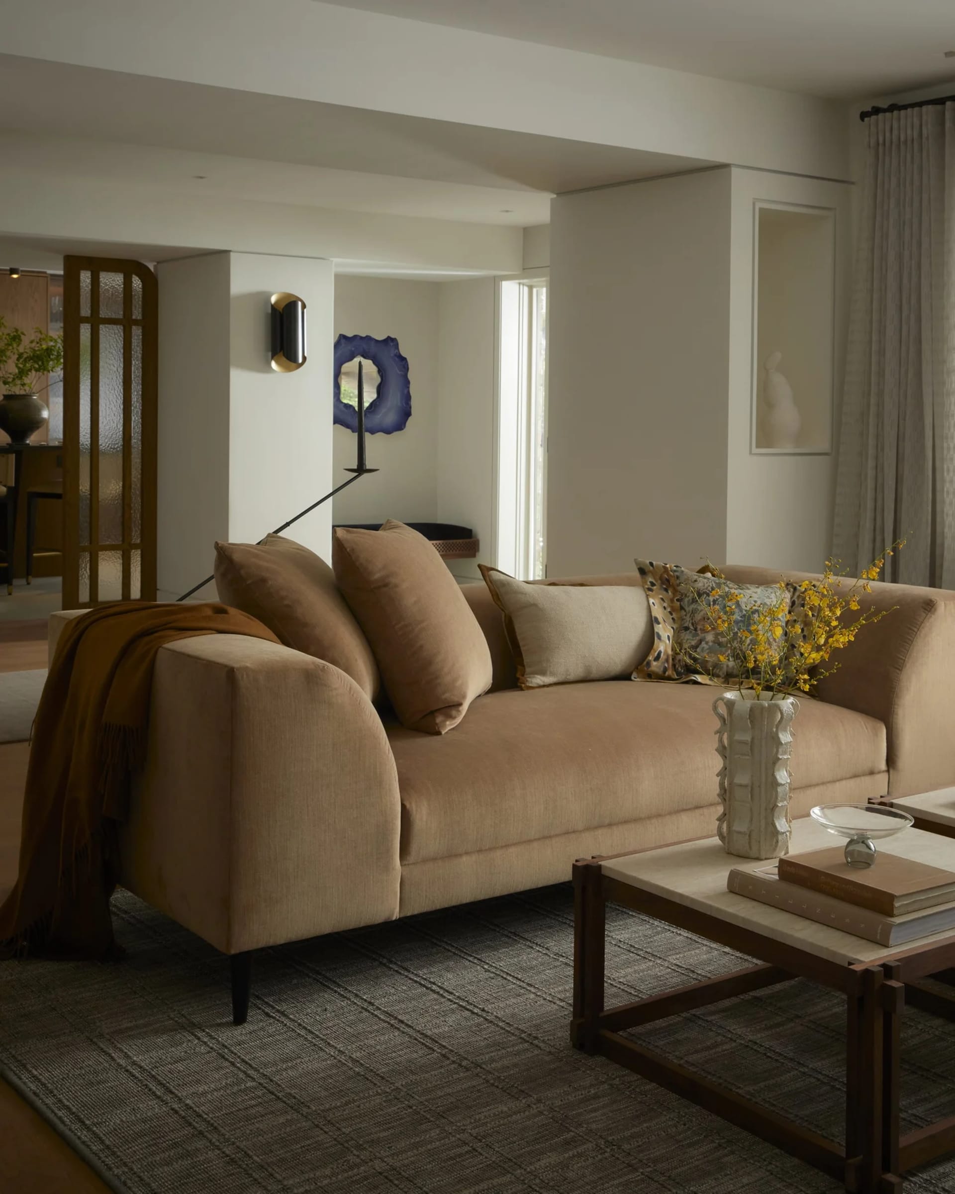 Modern living room with neutral-toned furniture and fabric, featuring a comfortable sofa with throw pillows, wood coffee tabl