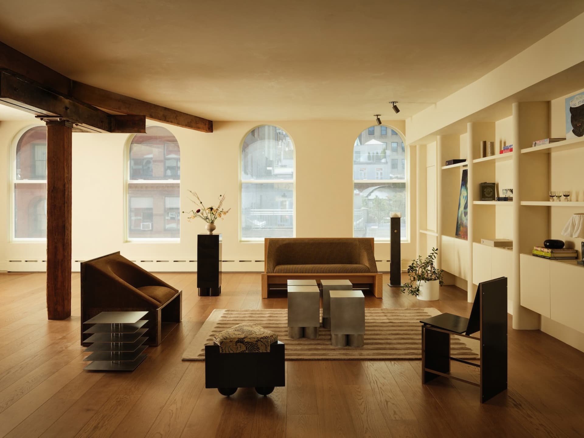 A modern living room featuring wooden flooring, a minimalist sofa, and sleek, geometric furniture.