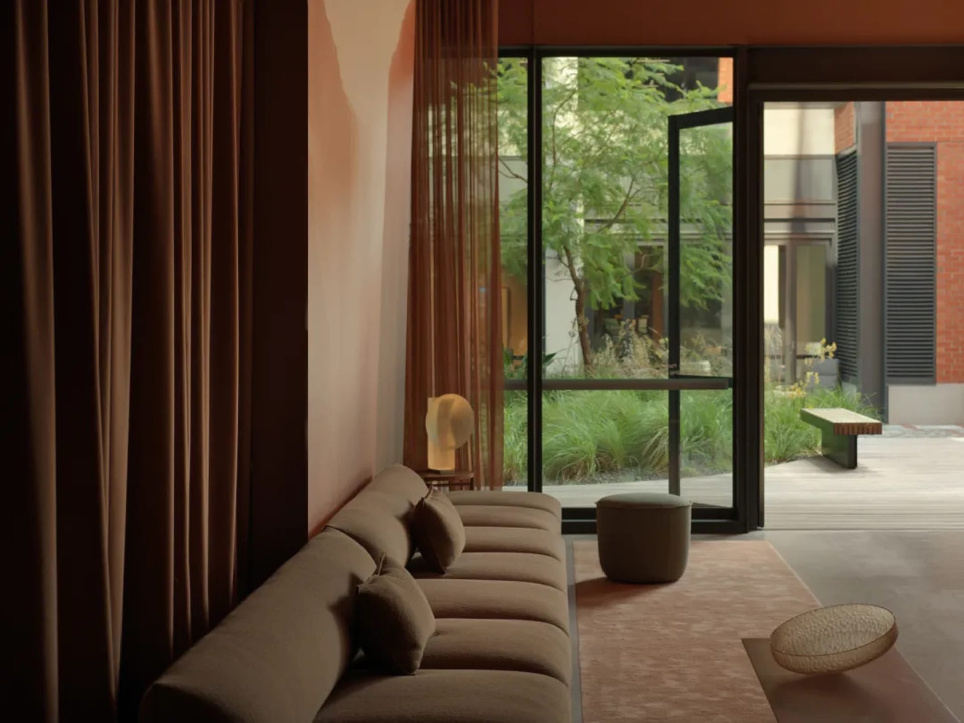 Modern minimalist living room with fabric seating, glass panel, and wooden furniture.