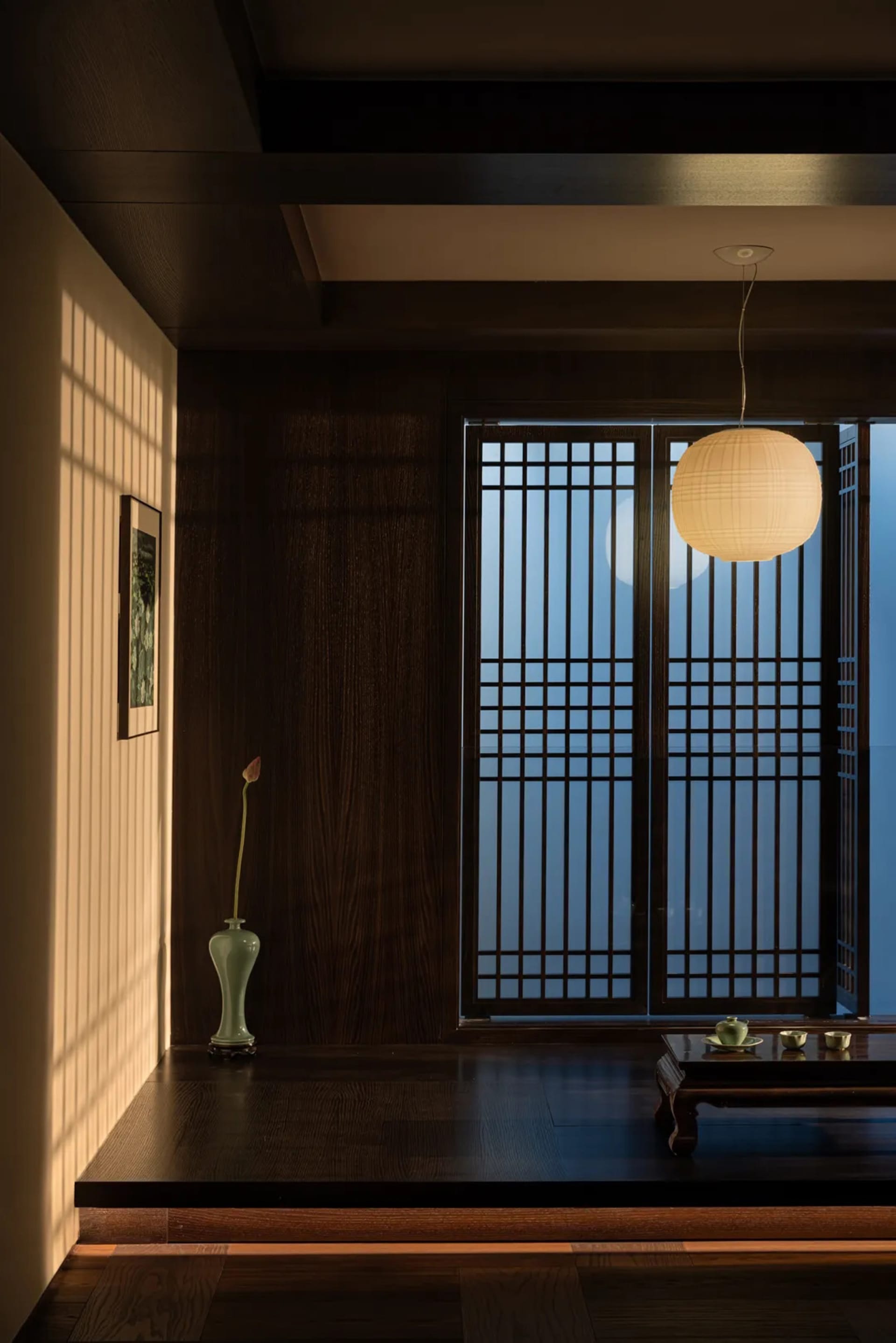 Modern living room featuring wooden paneled walls, a hanging light fixture, and a low coffee table.