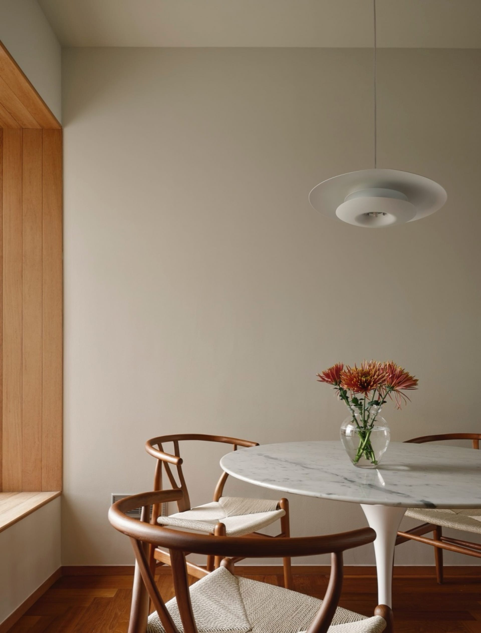 A minimalist dining room with a marble table and wooden chairs.