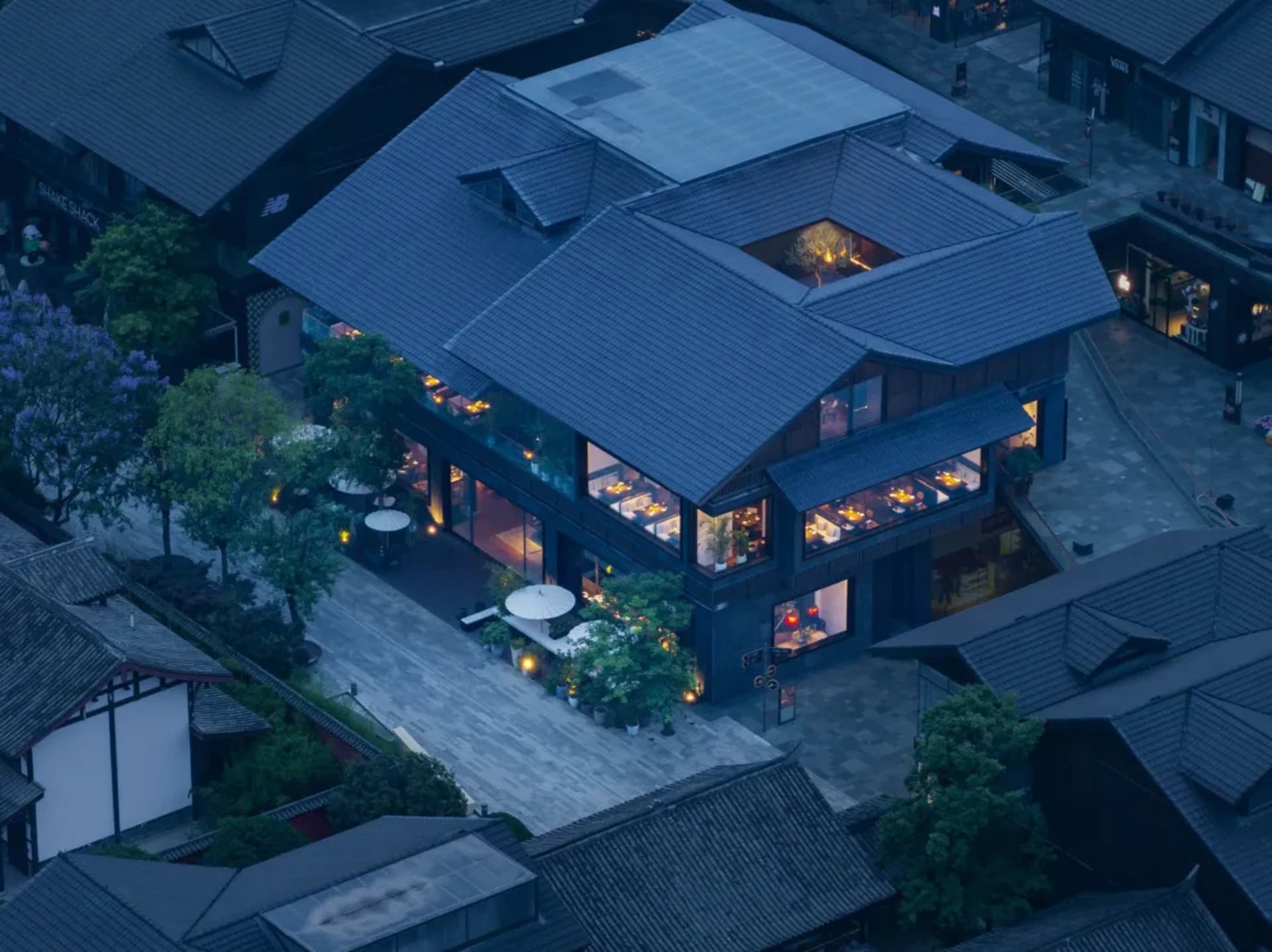 黃昏時分俯瞰傳統泥土餐廳外觀,擁有大型落地窗可見餐桌,木質地板