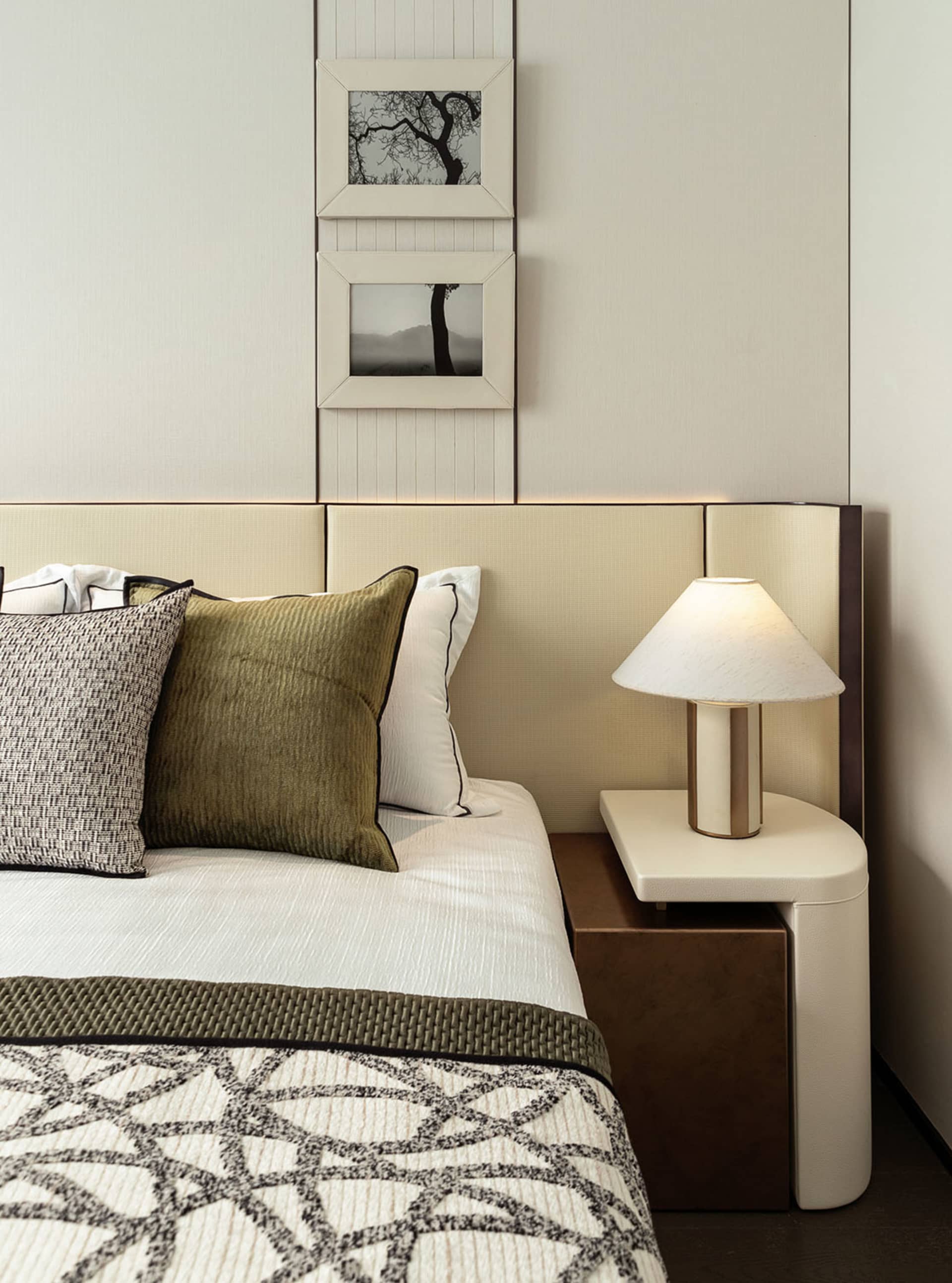 Modern minimalist bedroom with a white leather headboard, green fabric bedding, and beige accents.