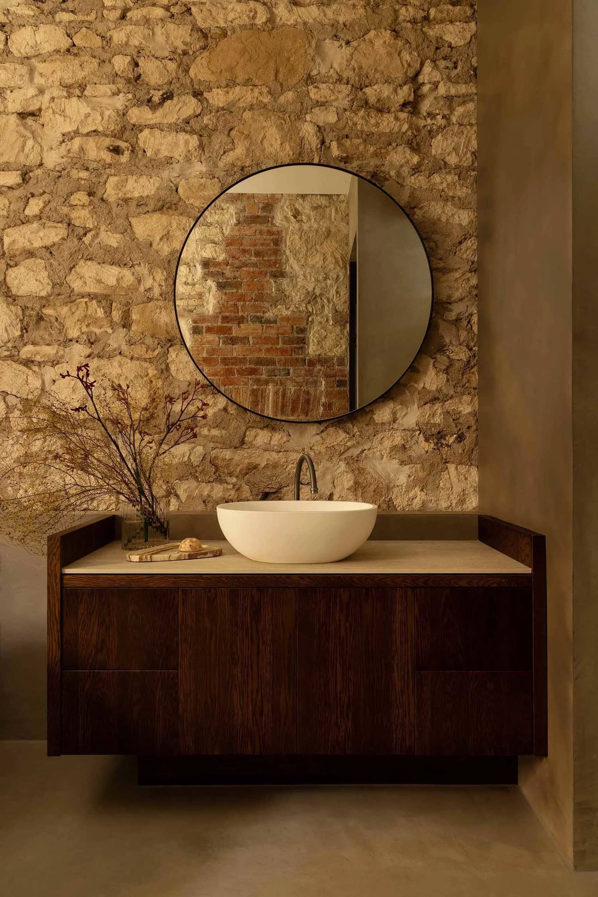 Modern bathroom with stone wall, wooden vanity, and marble countertop.