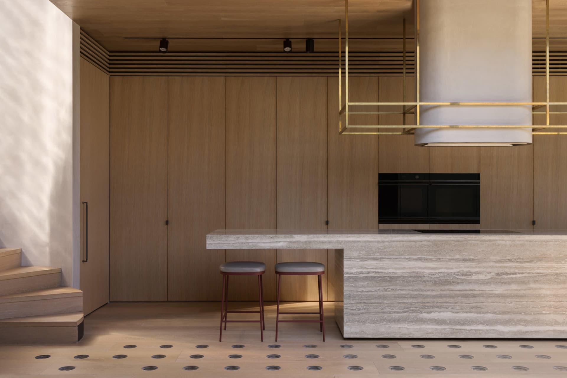 A modern residential kitchen featuring wooden cabinets, marble countertops, and brass handy fasteners.
