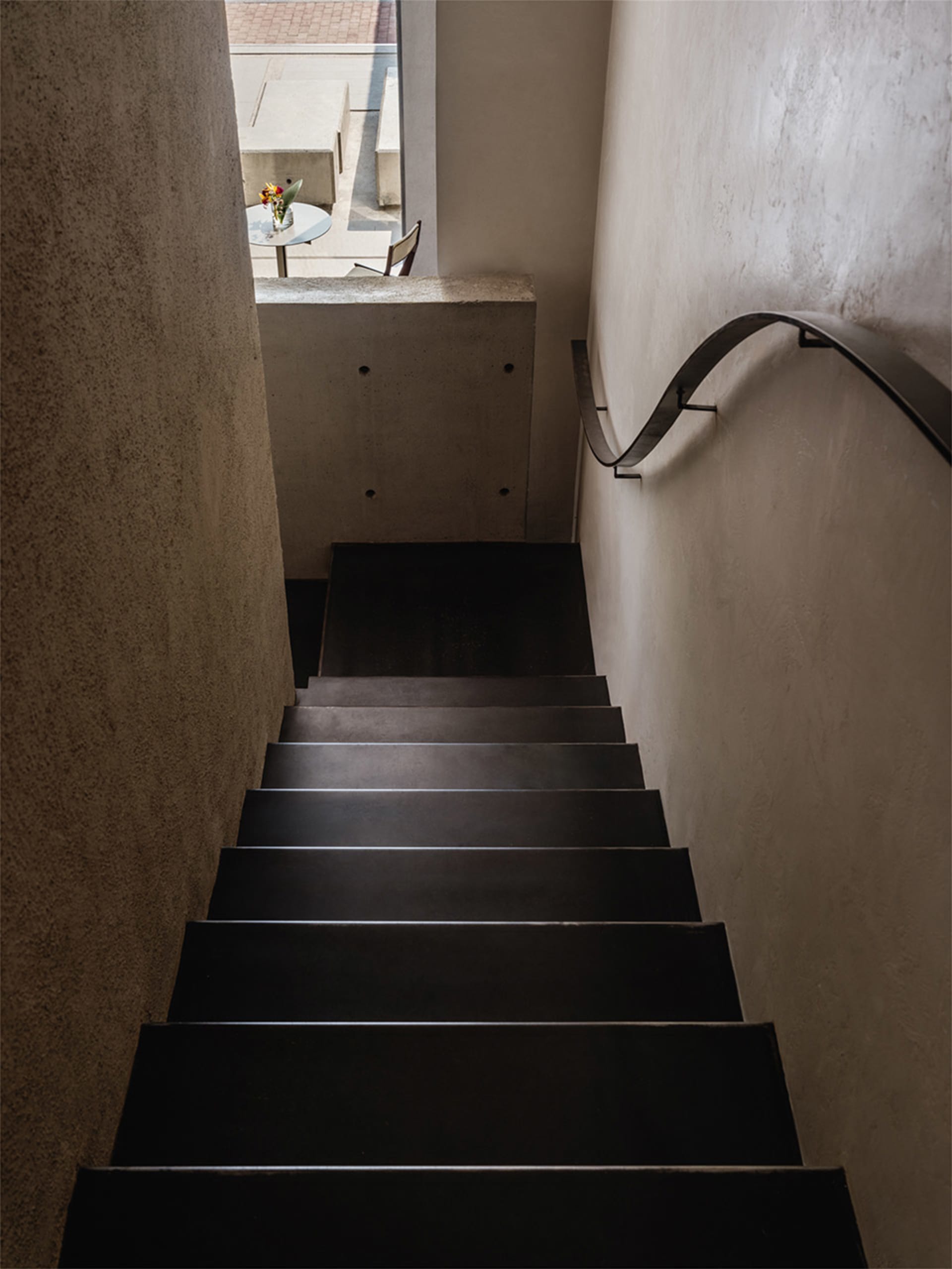 A modern metal staircase with a curved handrail in an interior space.