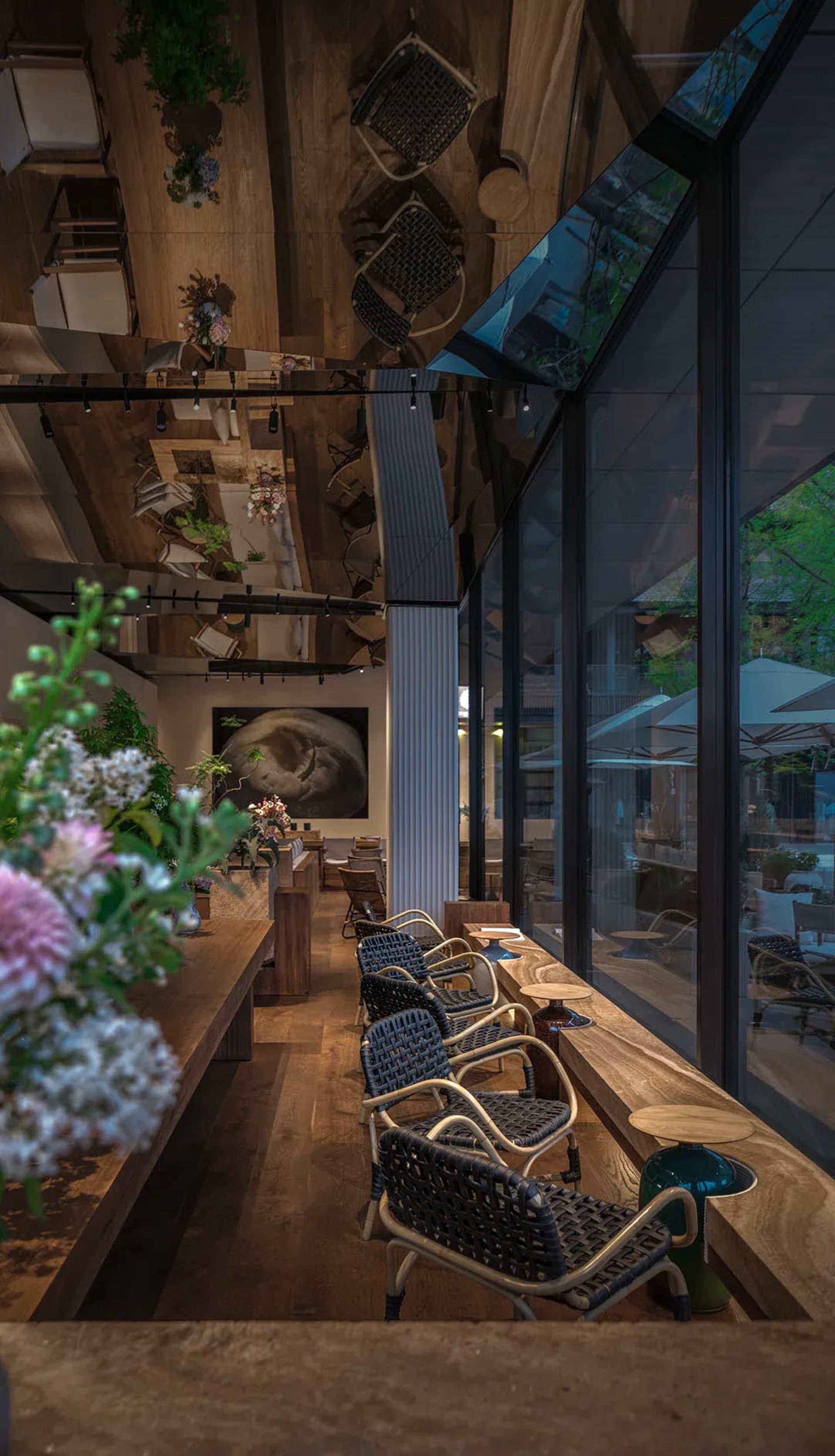 A cozy cafe interior with wooden tables and chairs, canvas seats, and potted plants.