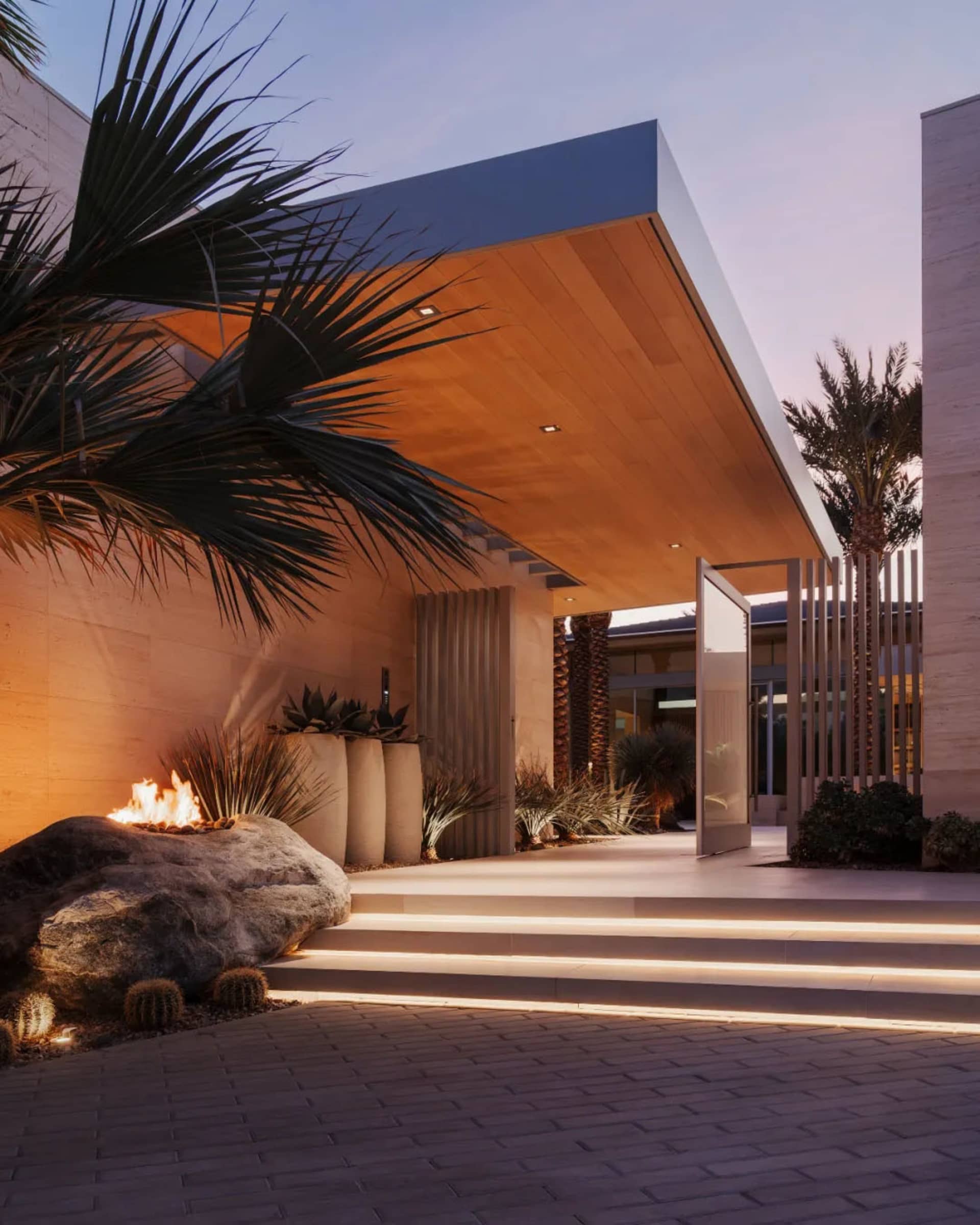 Exterior view of a modern entrance featuring concrete steps and glass doors, set against a dusk sky.