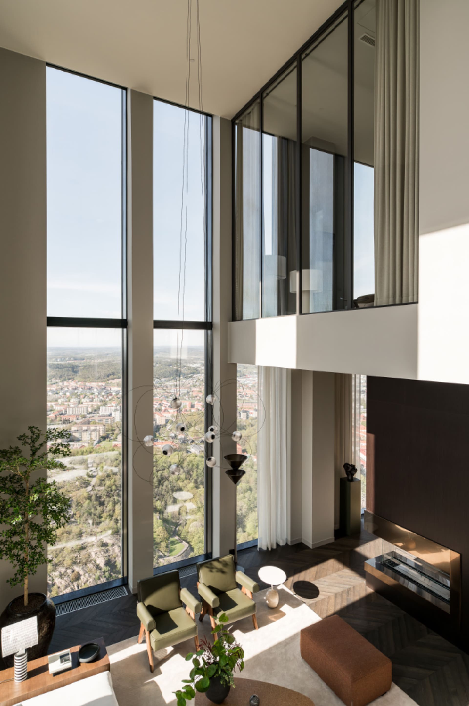 A minimalist living room with large glass windows, wooden furniture, and a fireplace.