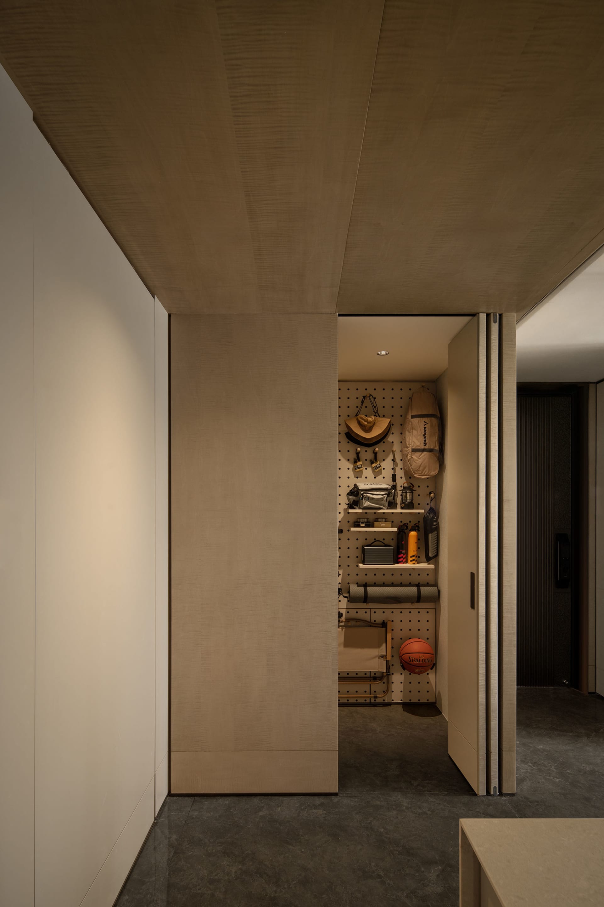 A minimalist closet with wooden walls and a pegboard for organizing items.